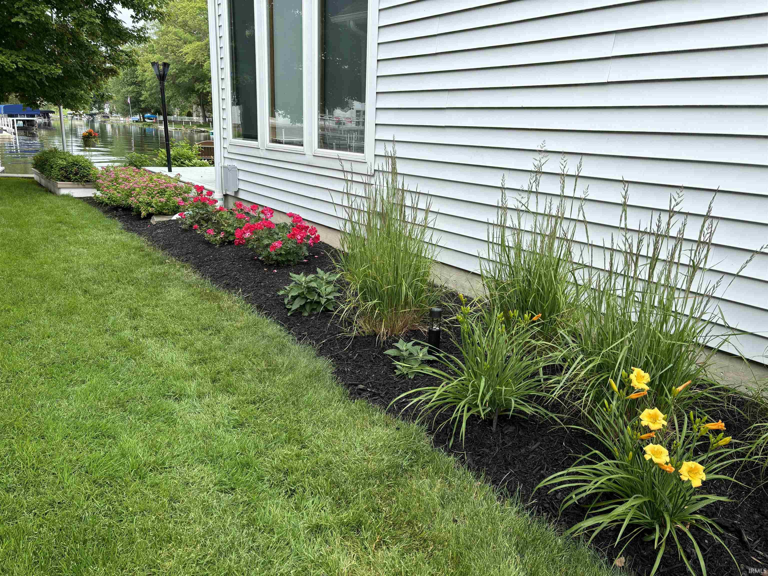 Manicured lawn with a landscaped garden bed featuring mixed plantings and dark mulch