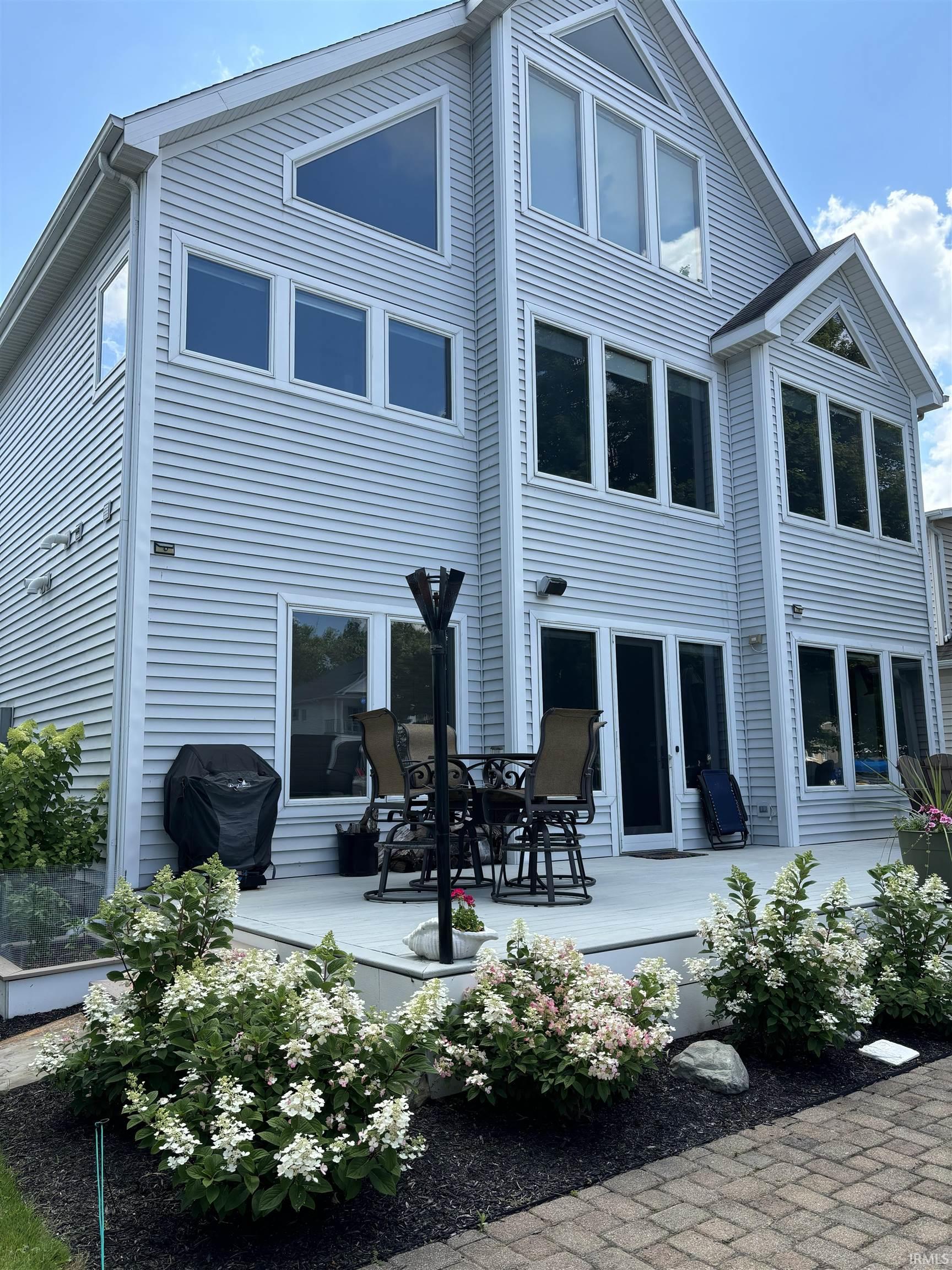 Multi-level exterior featuring light-colored siding, a patio deck, and a brick paver pathway