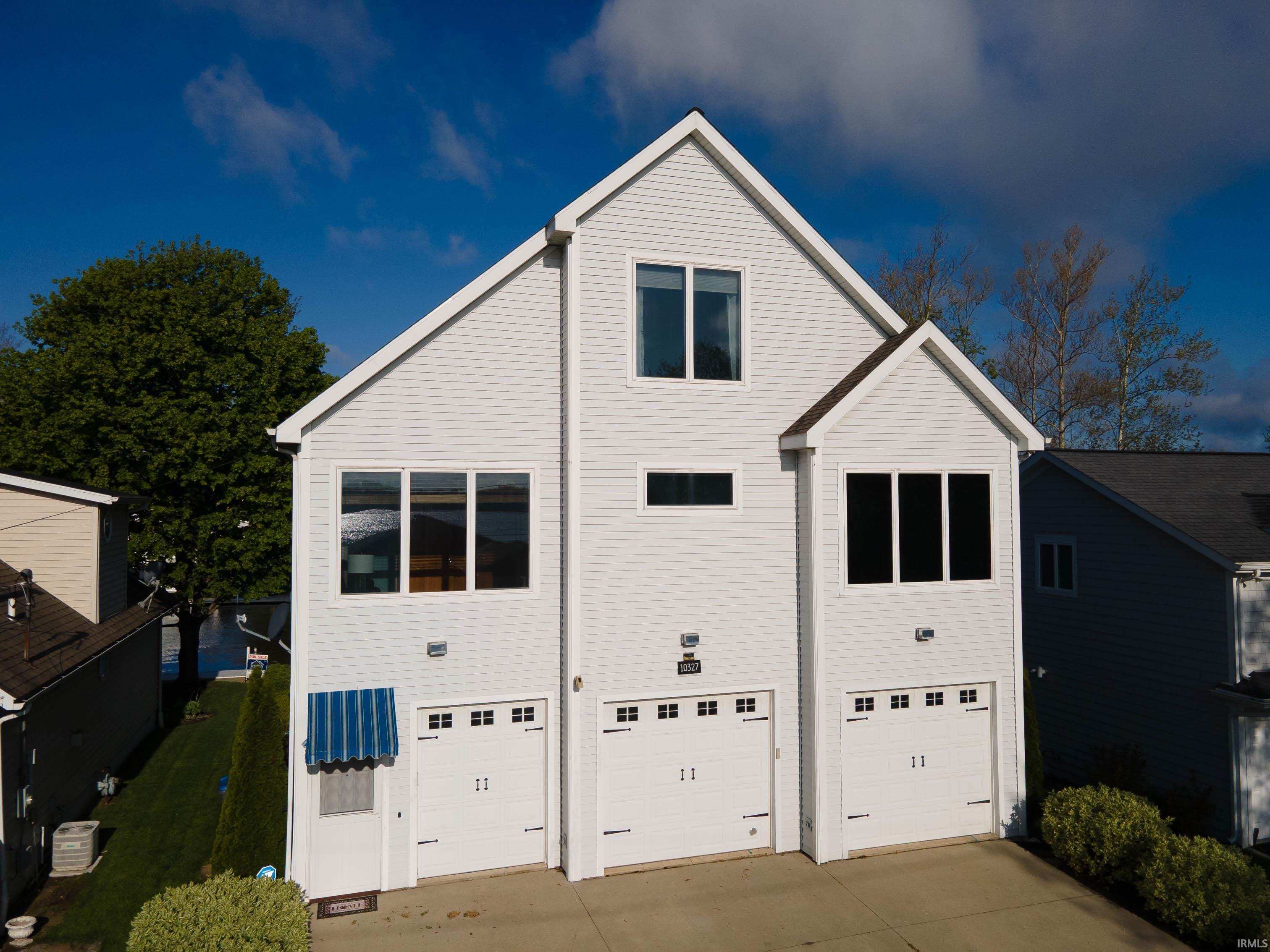 Contemporary three-story residence featuring white siding and prominent gabled roofs