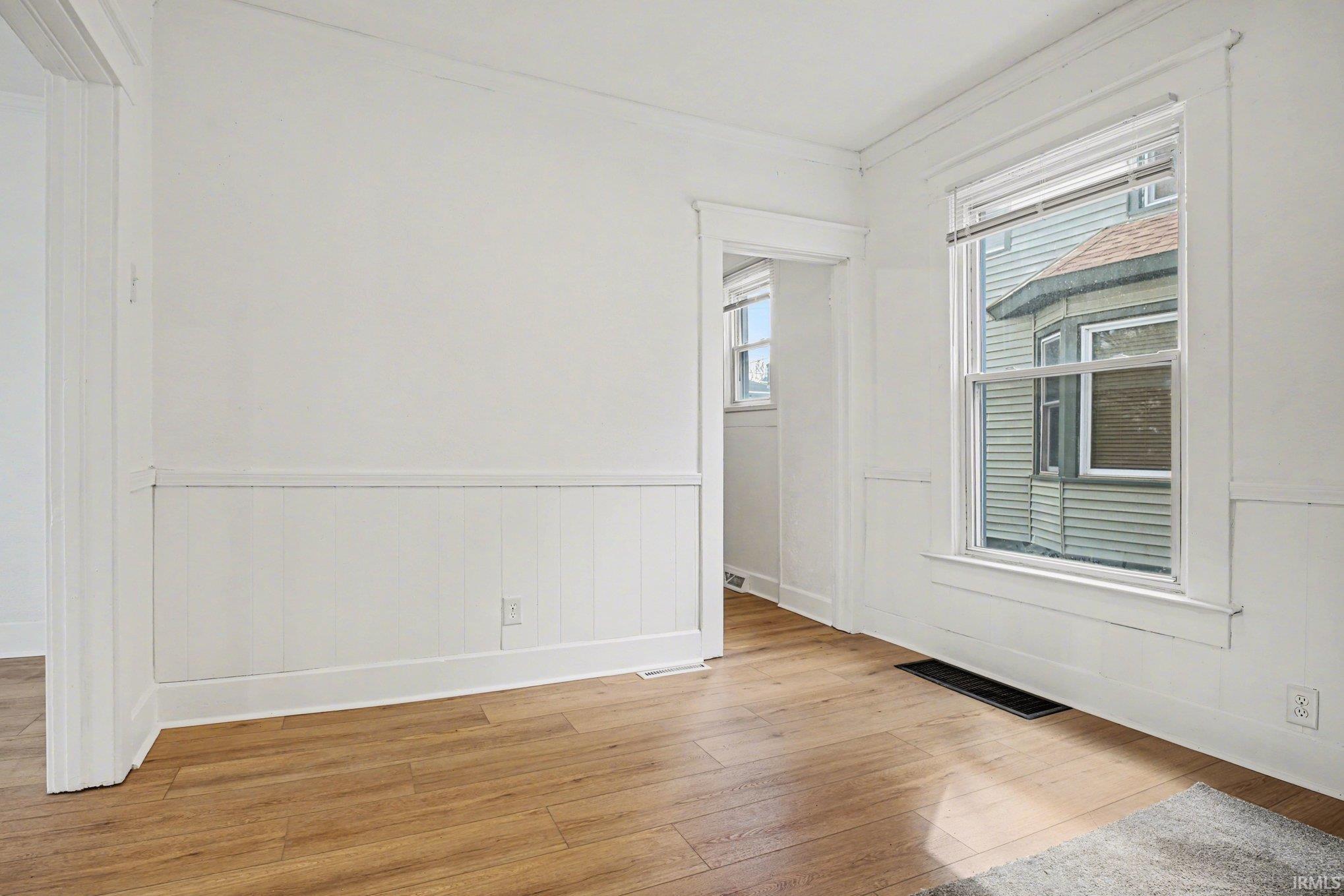Interior space featuring wood-finish flooring, white paneled wainscoting, and white trim