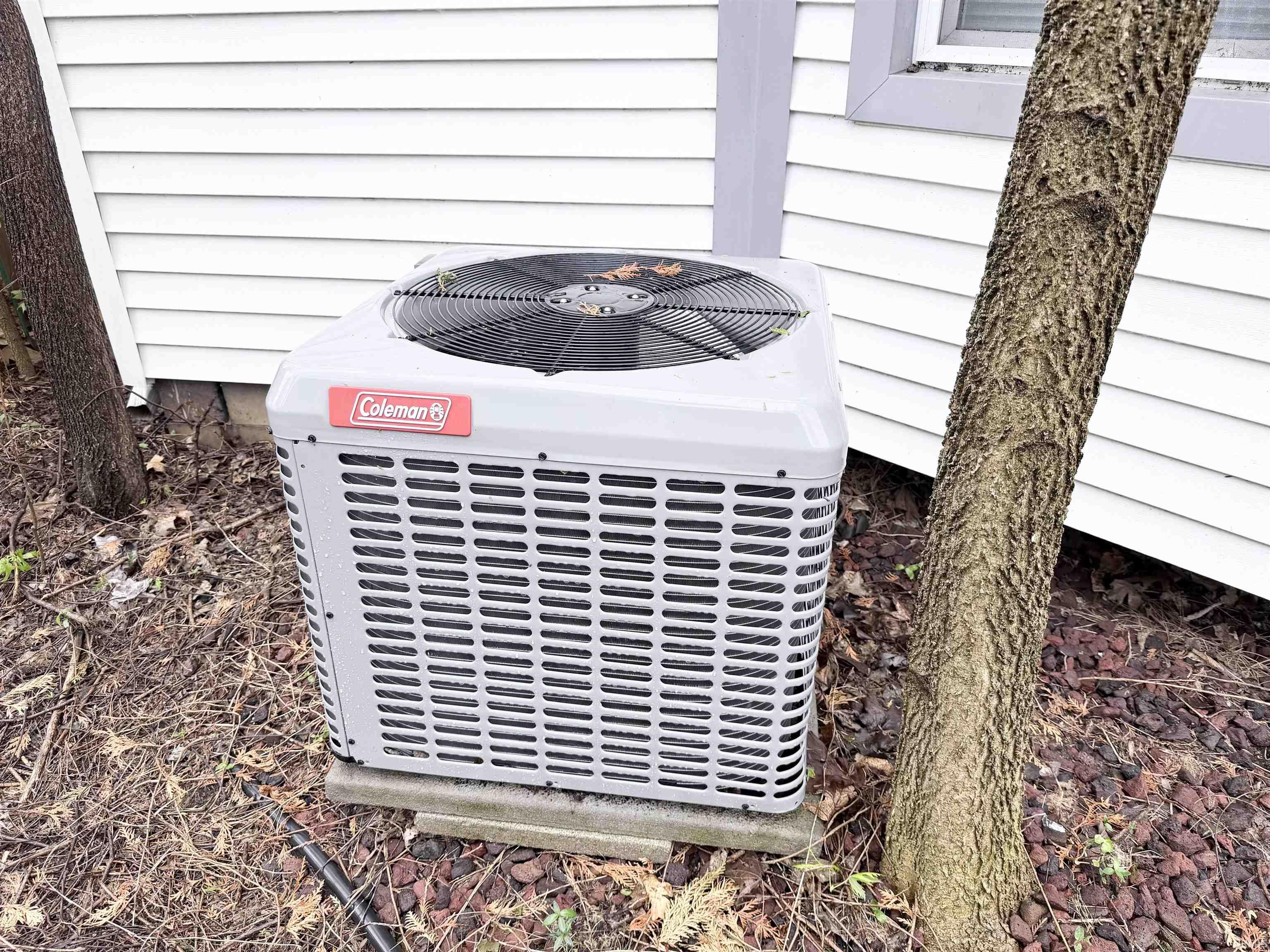 Coleman brand external HVAC unit on a concrete pad, positioned against white horizontal siding