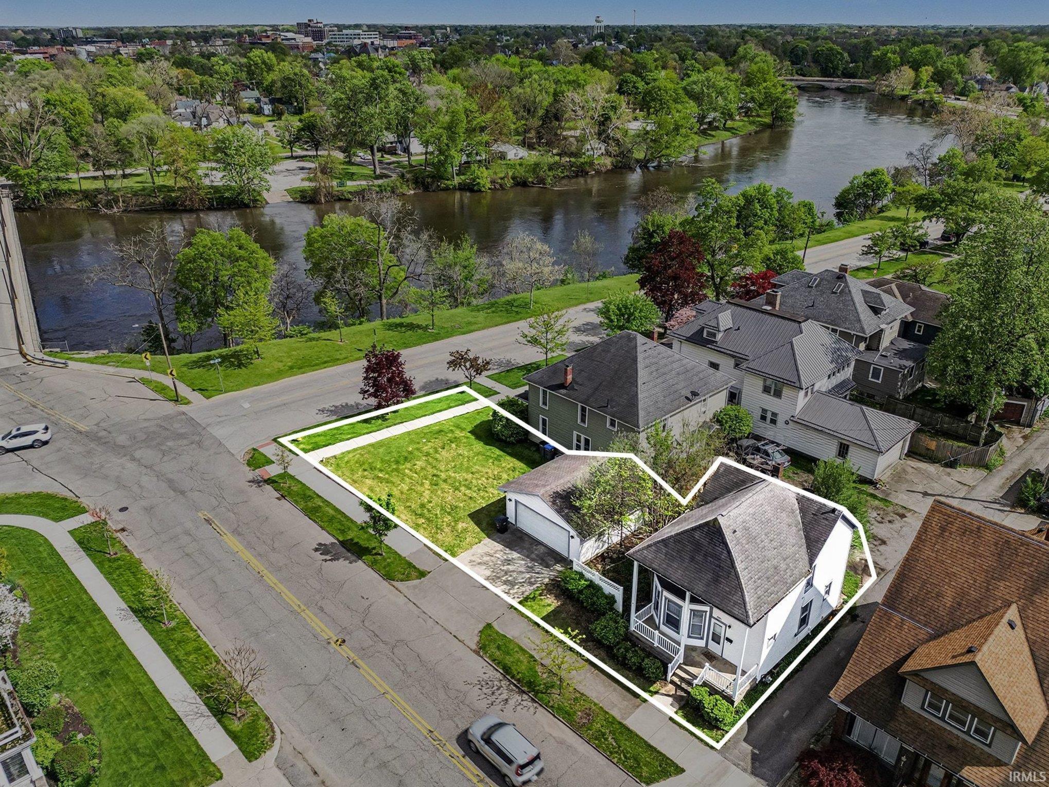 Aerial view showcasing a white two-story residence with a multi-gabled roof and a front porch