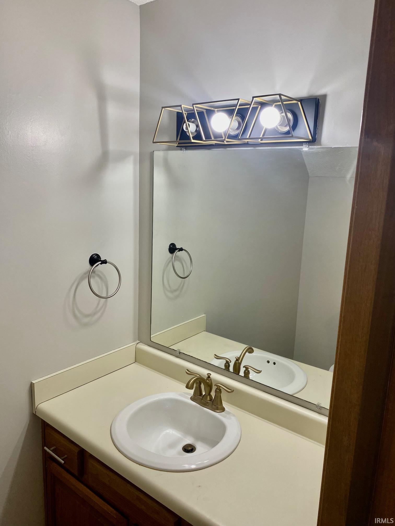 Vanity featuring an integrated sink, a gold-toned faucet, and a wall-mounted mirror
