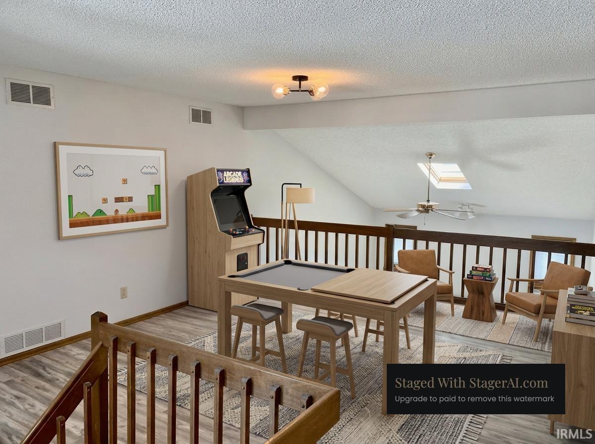 Open loft area with wood-finish flooring and a vaulted ceiling