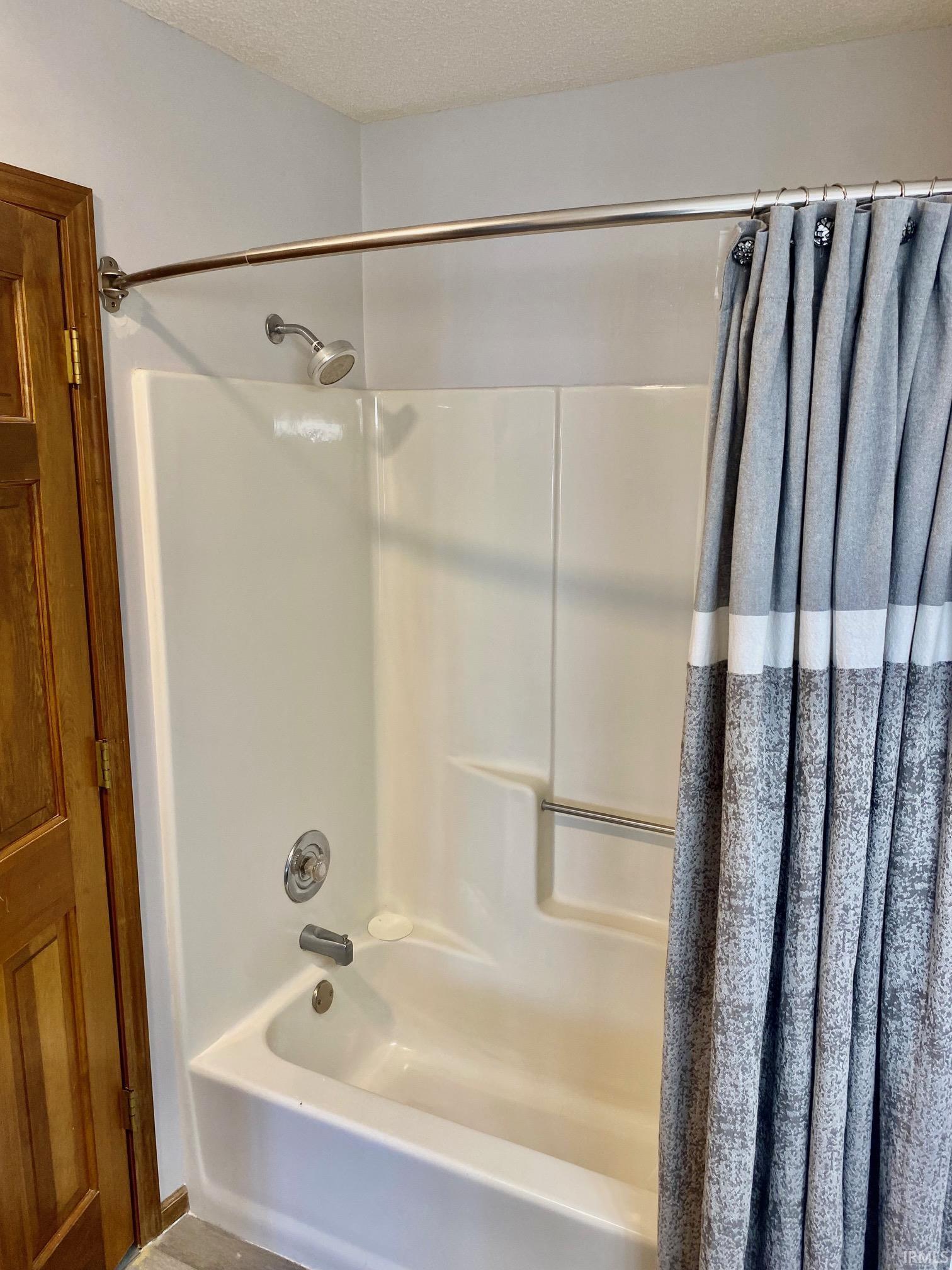 White fiberglass tub and shower combination with chrome fixtures