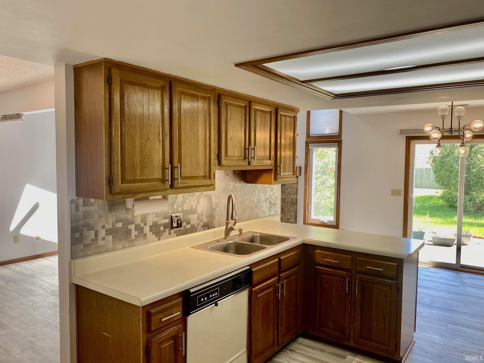 Kitchen featuring wood cabinetry, a dual basin stainless steel sink, and a tiled backsplash