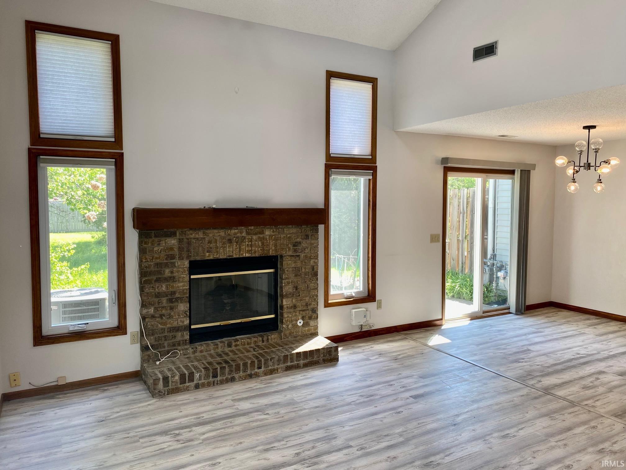 Vaulted ceilings over a brick fireplace with a wood mantle