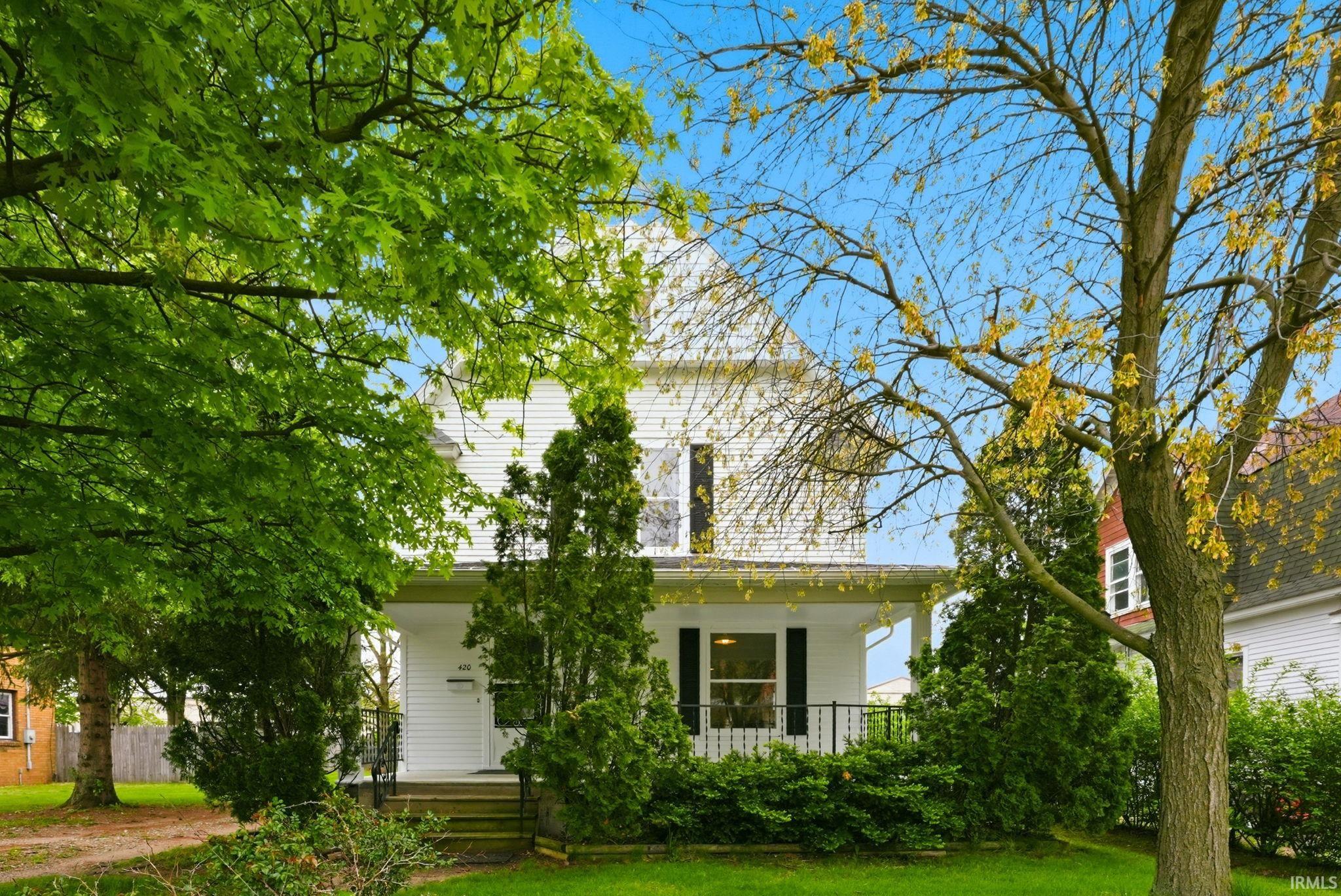 White clapboard siding exterior with a covered front porch featuring a black metal railing