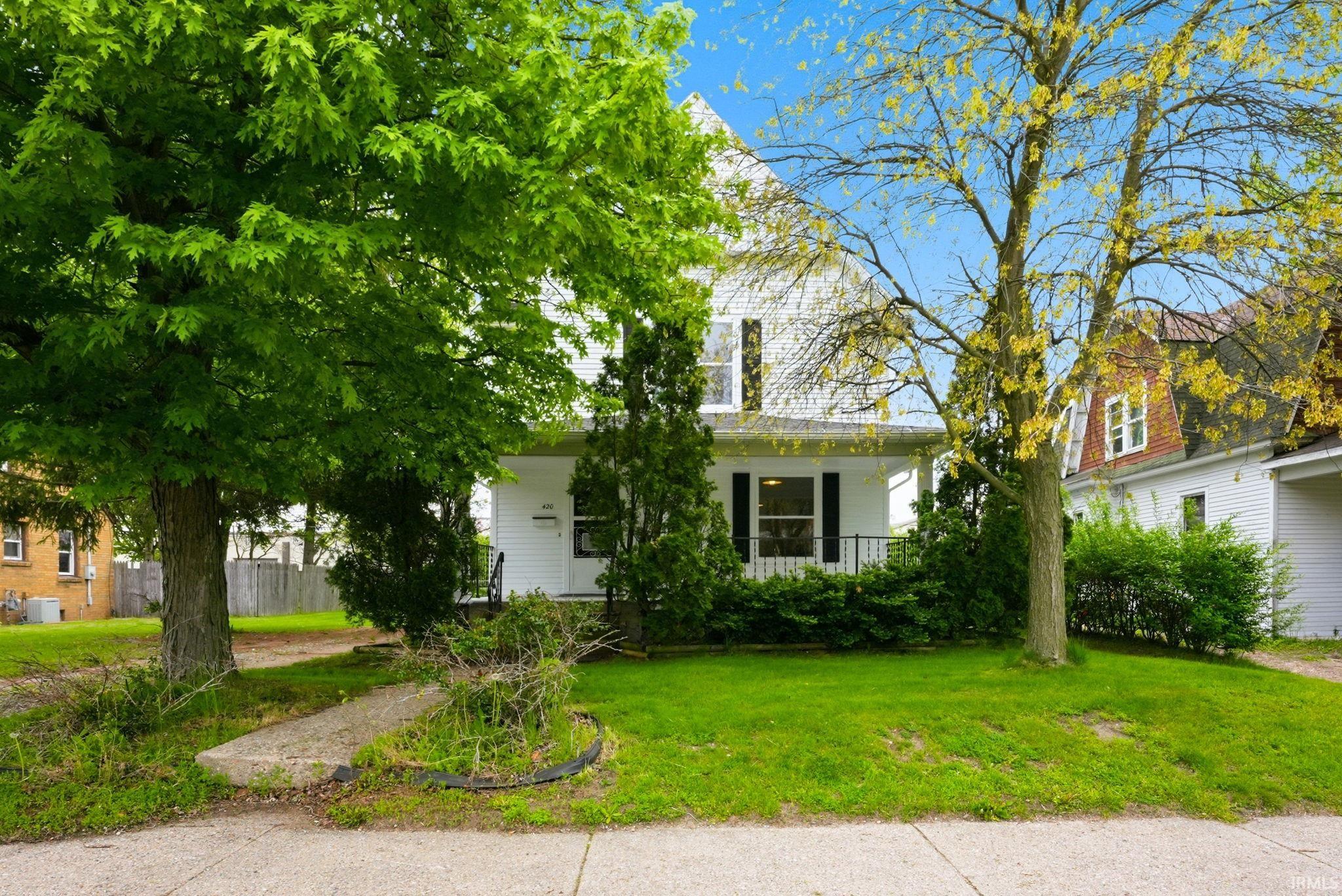 White two-story residence with a covered porch and dark window shutters