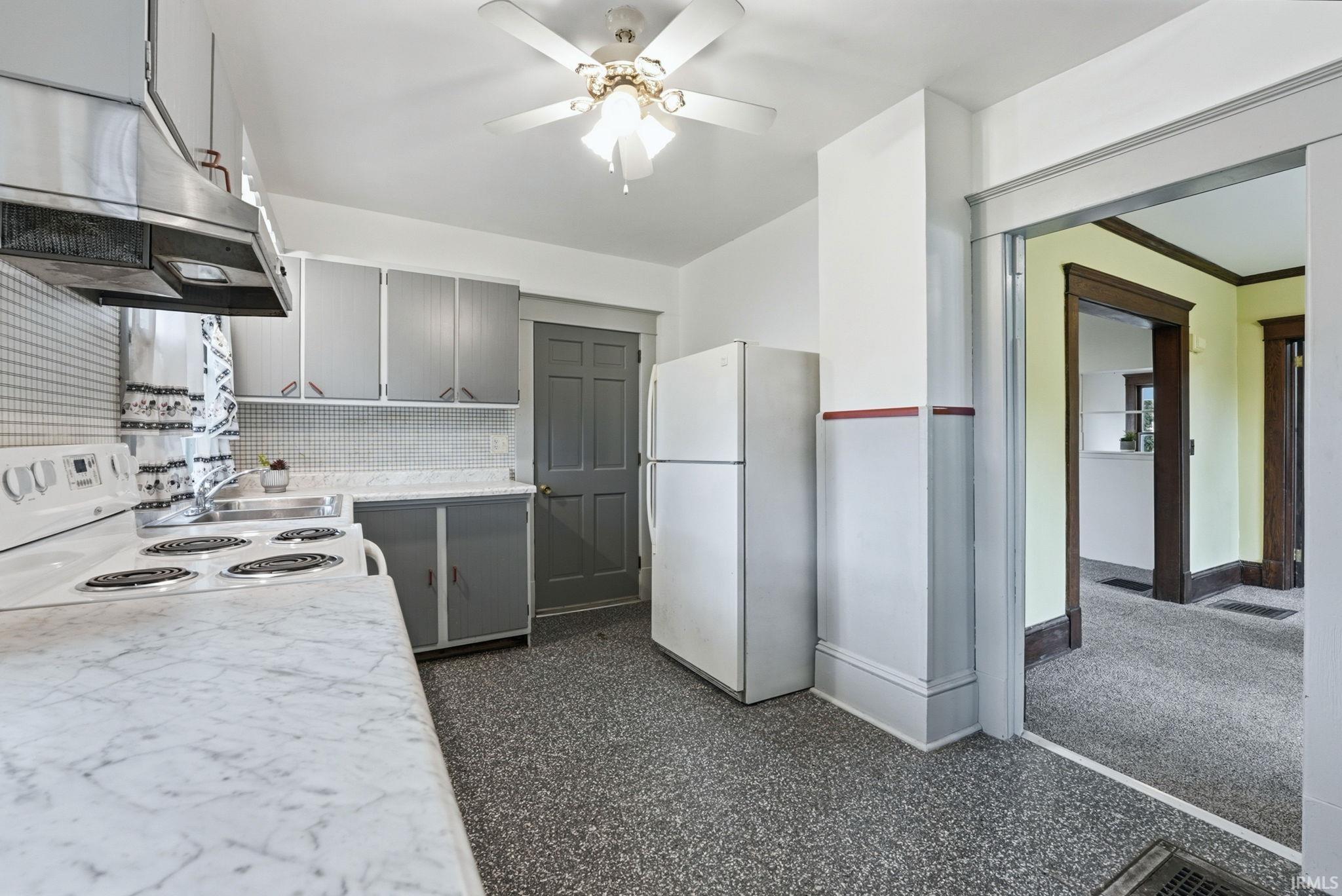 Kitchen featuring a ceiling fan with light fixture, gray cabinetry, white countertops, stainless steel range hood, and speckled flooring