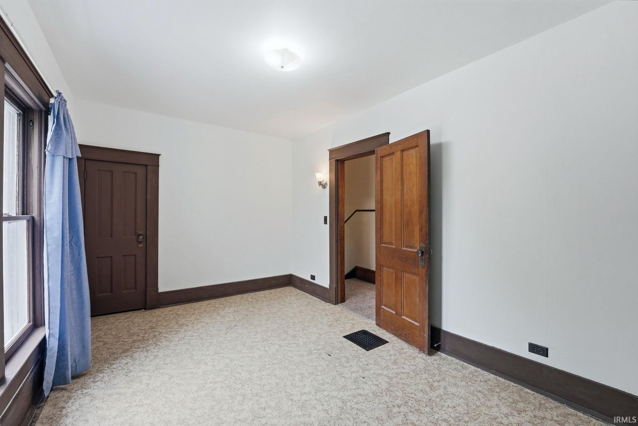 Room featuring light-colored patterned carpeting, white walls, and dark wood trim