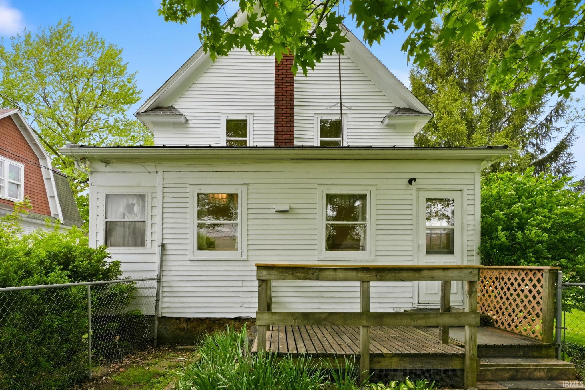 White clapboard siding exterior with a wood deck featuring lattice work
