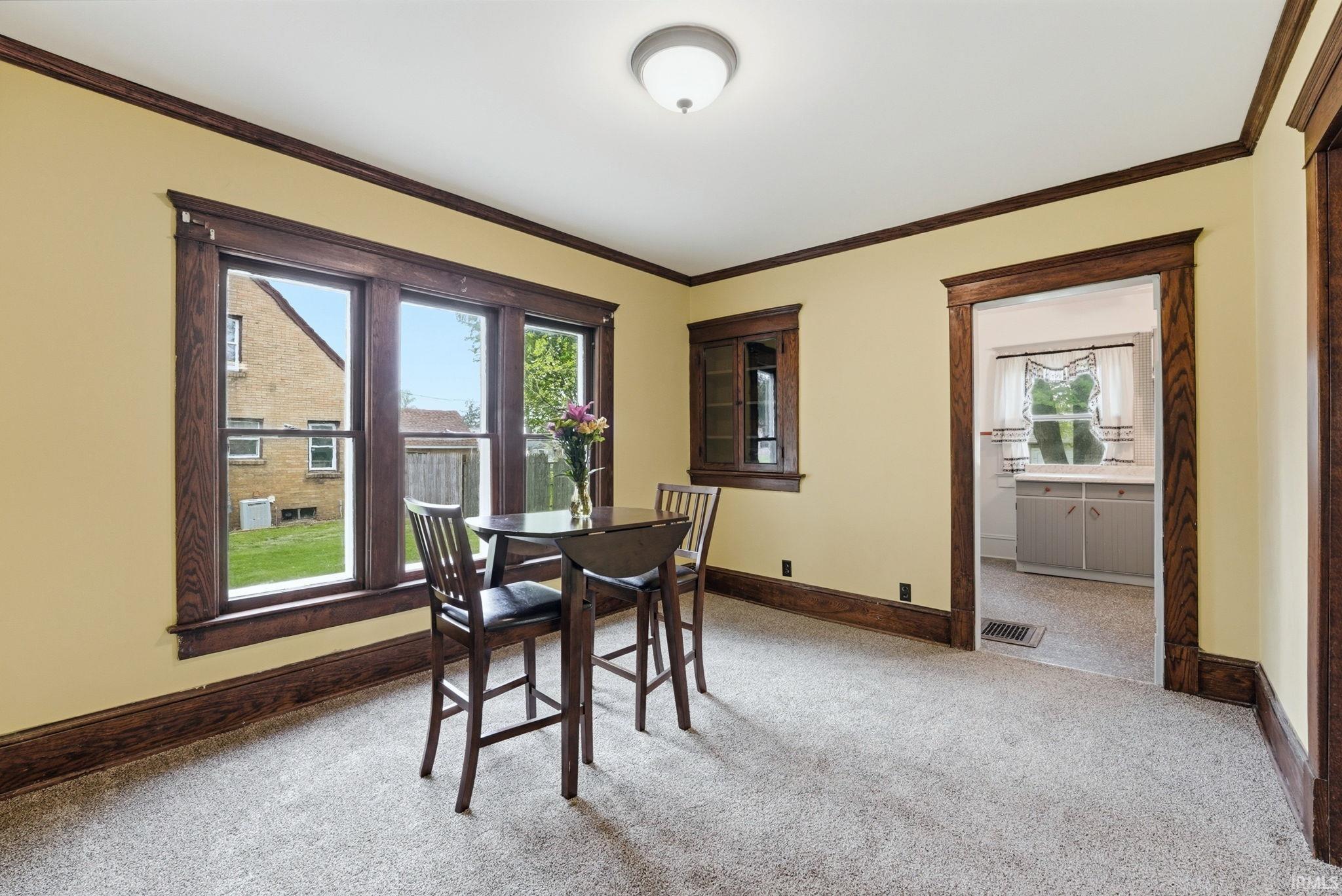 Carpeted room featuring a ceiling-mounted light fixture and multiple windows with dark wood trim