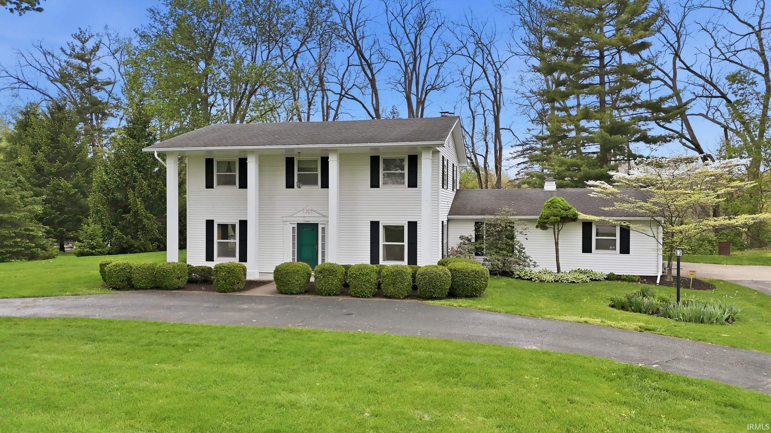 Colonial-style residence featuring a white exterior, black shutters, and a bright green front door