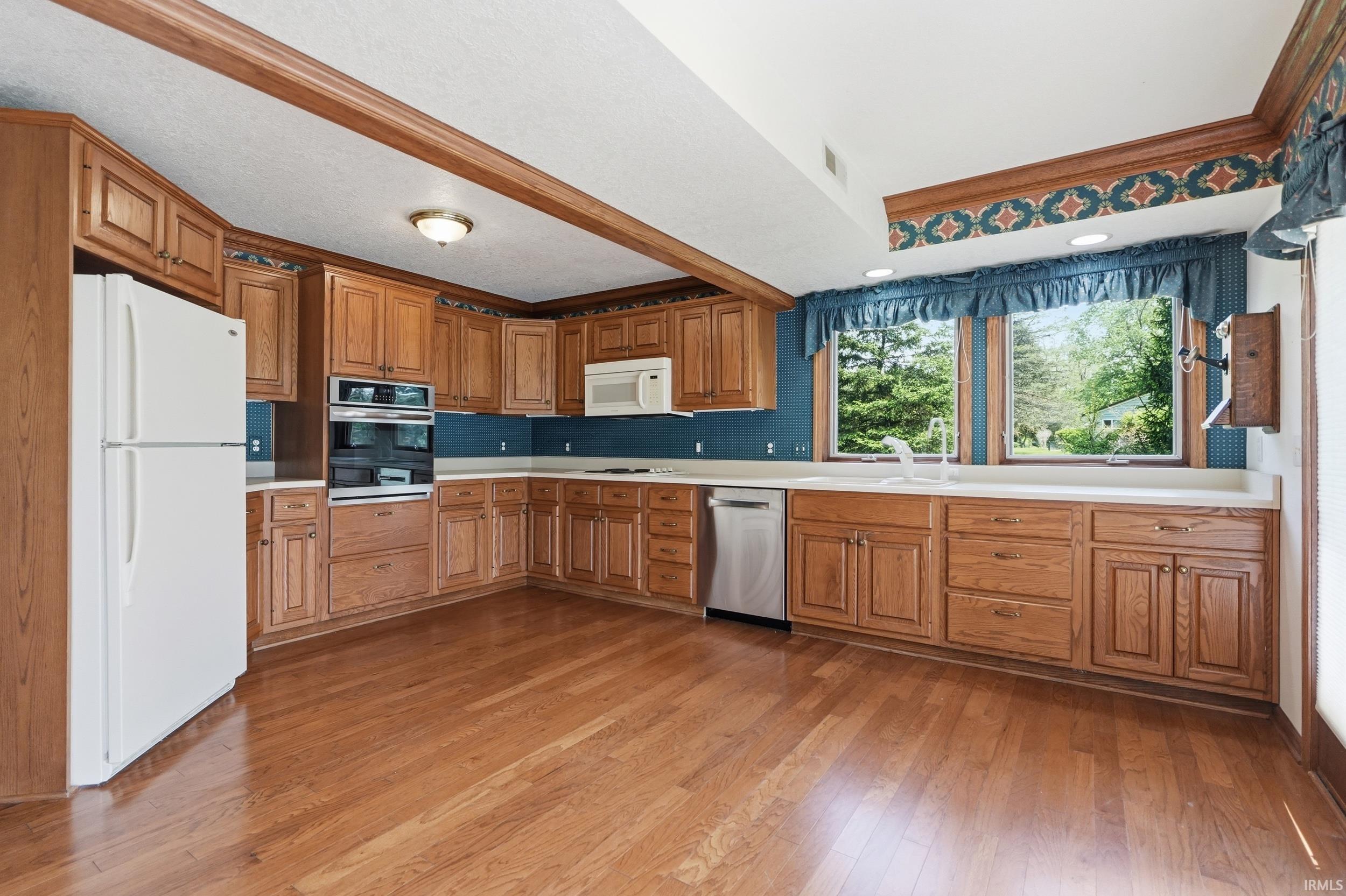 Spacious kitchen featuring extensive wood cabinetry, wood-finish flooring, and white countertops