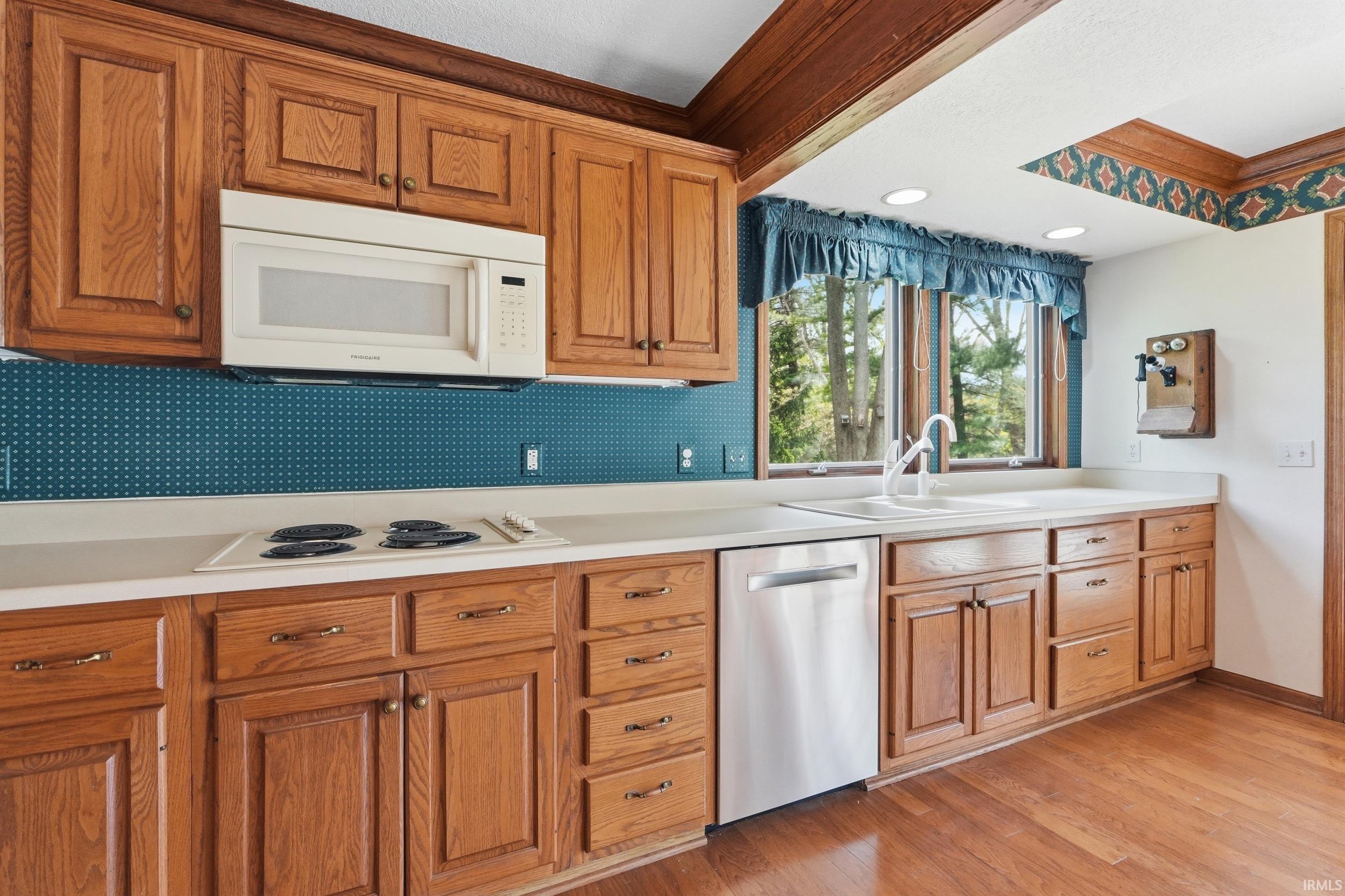 Kitchen featuring wood cabinetry, white countertops, a stainless steel dishwasher, an electric cooktop, and an over-the-range microwave
