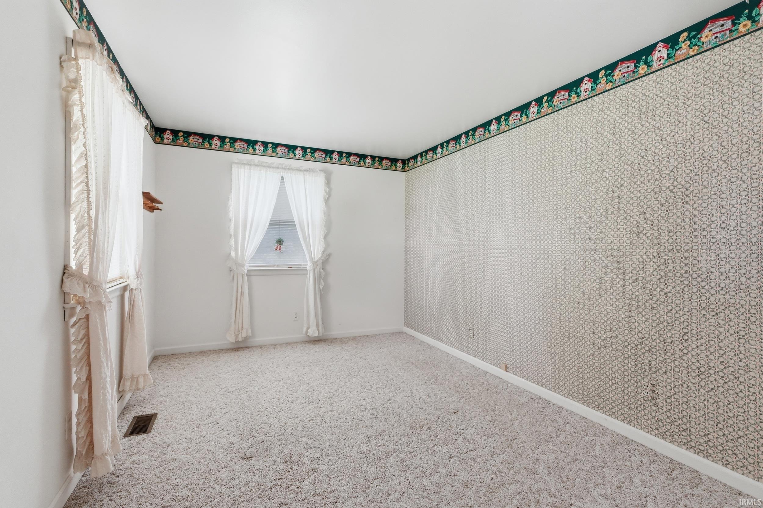 Expansive room featuring two windows, textured wall covering, and wall-to-wall carpeting