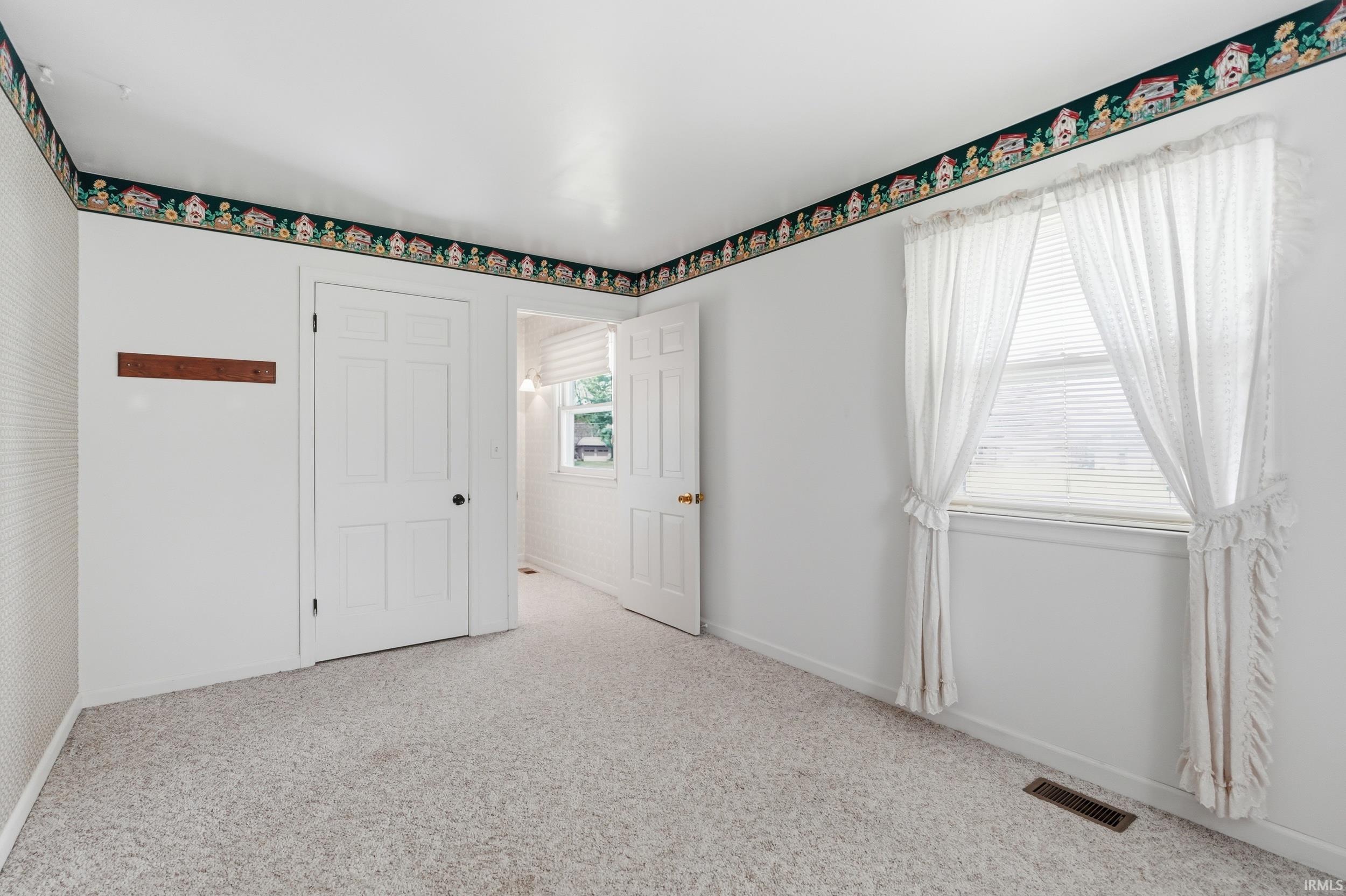 Carpeted interior space with white walls and a decorative border