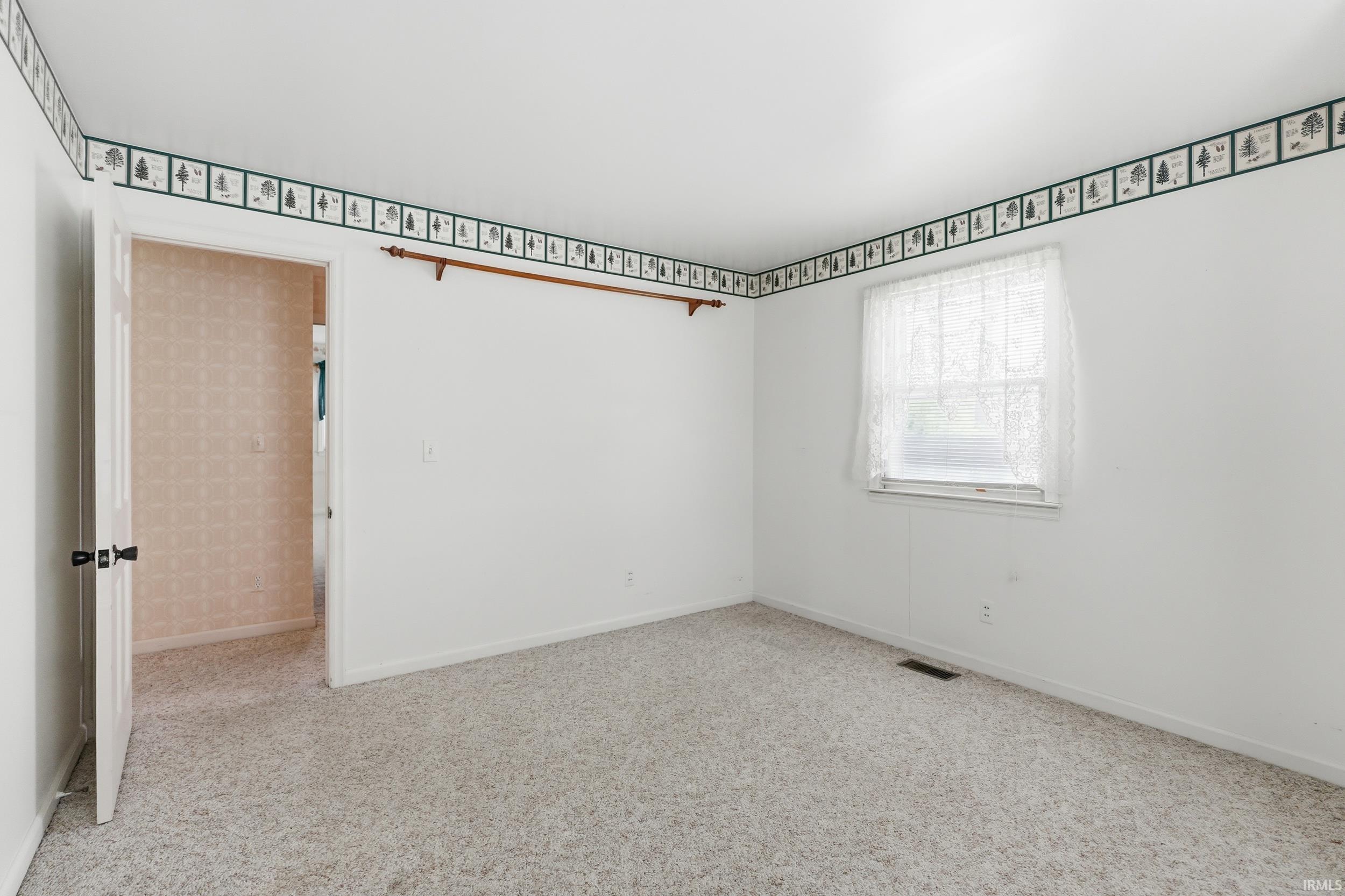 Carpeted room with a single window and neutral white walls