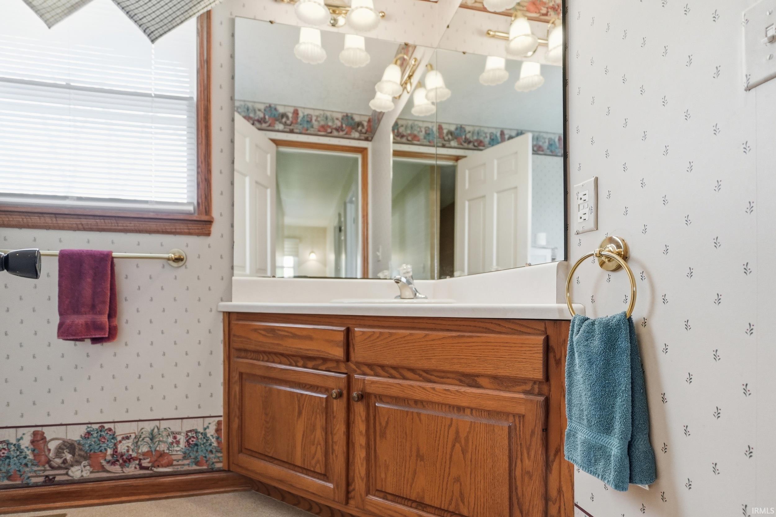 Bathroom vanity featuring wood cabinetry, integrated sink, and wall-mounted mirror