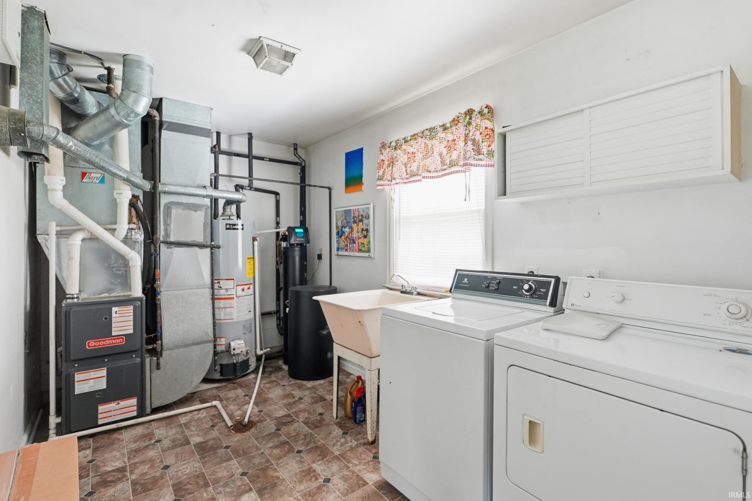 Dedicated laundry space featuring a utility sink, two large appliances, and a window