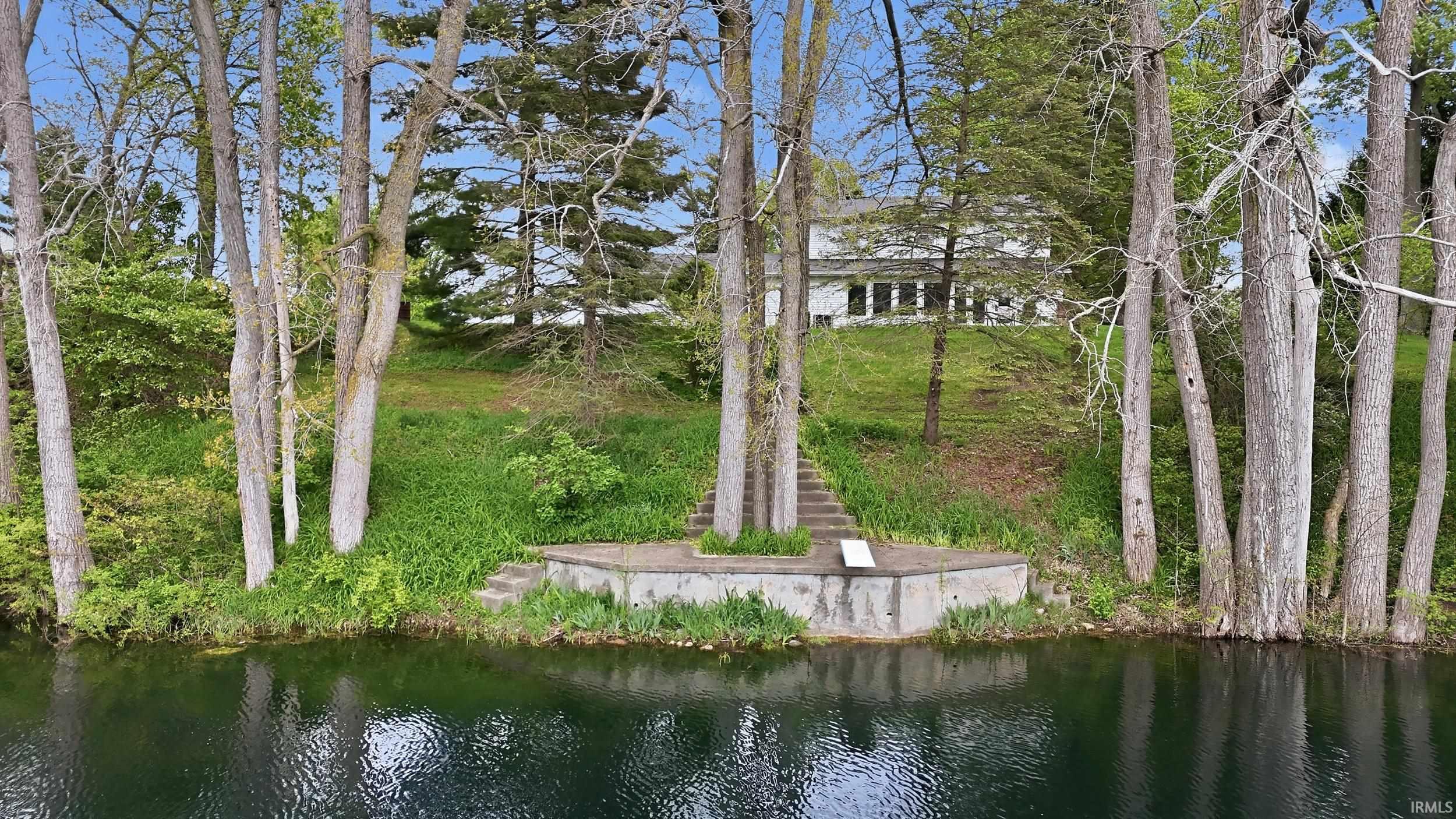 Waterfront setting featuring a concrete dock and stone steps