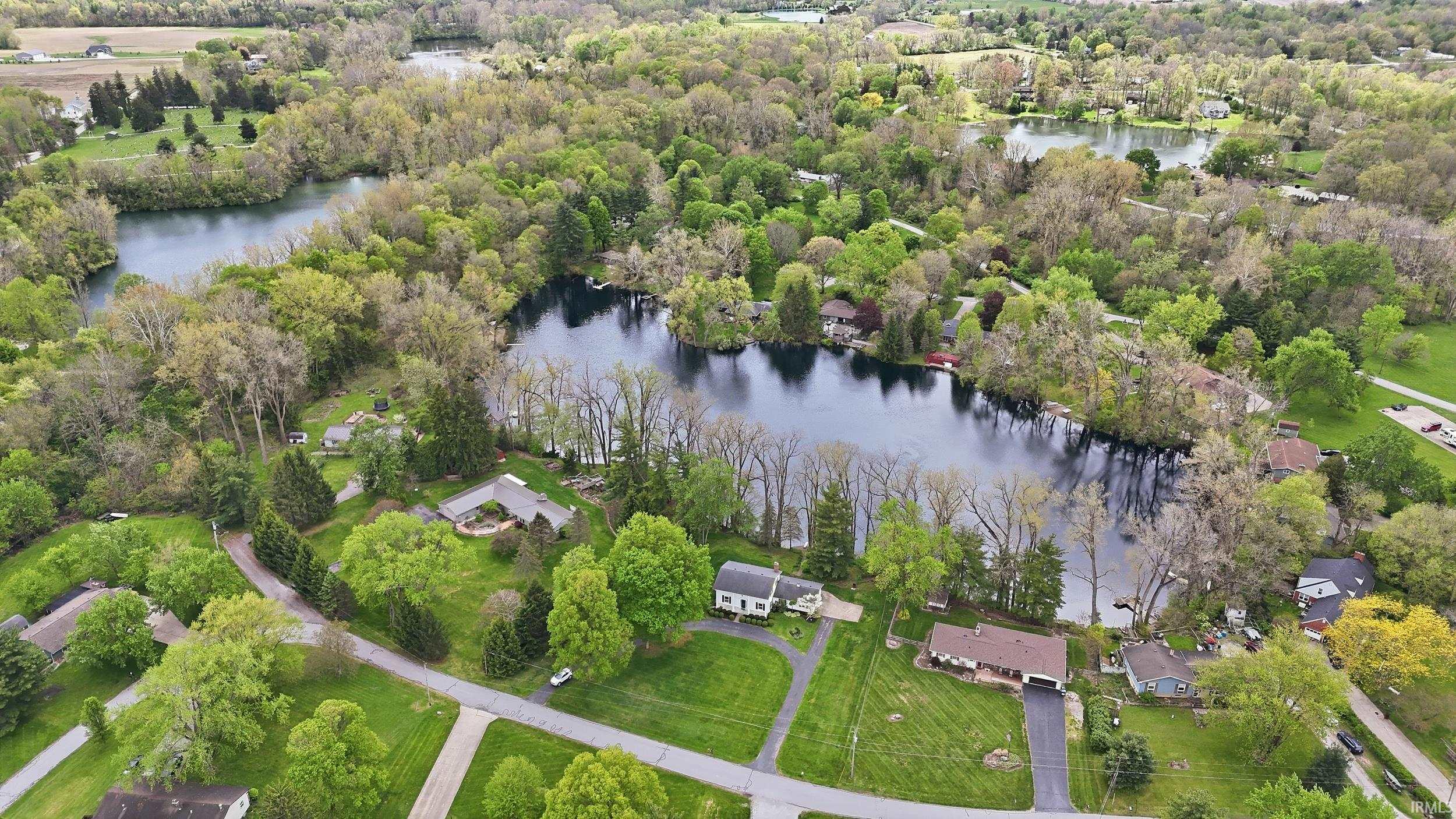 Expansive aerial perspective showcasing a significant body of water bordered by dense tree coverage and residential properties