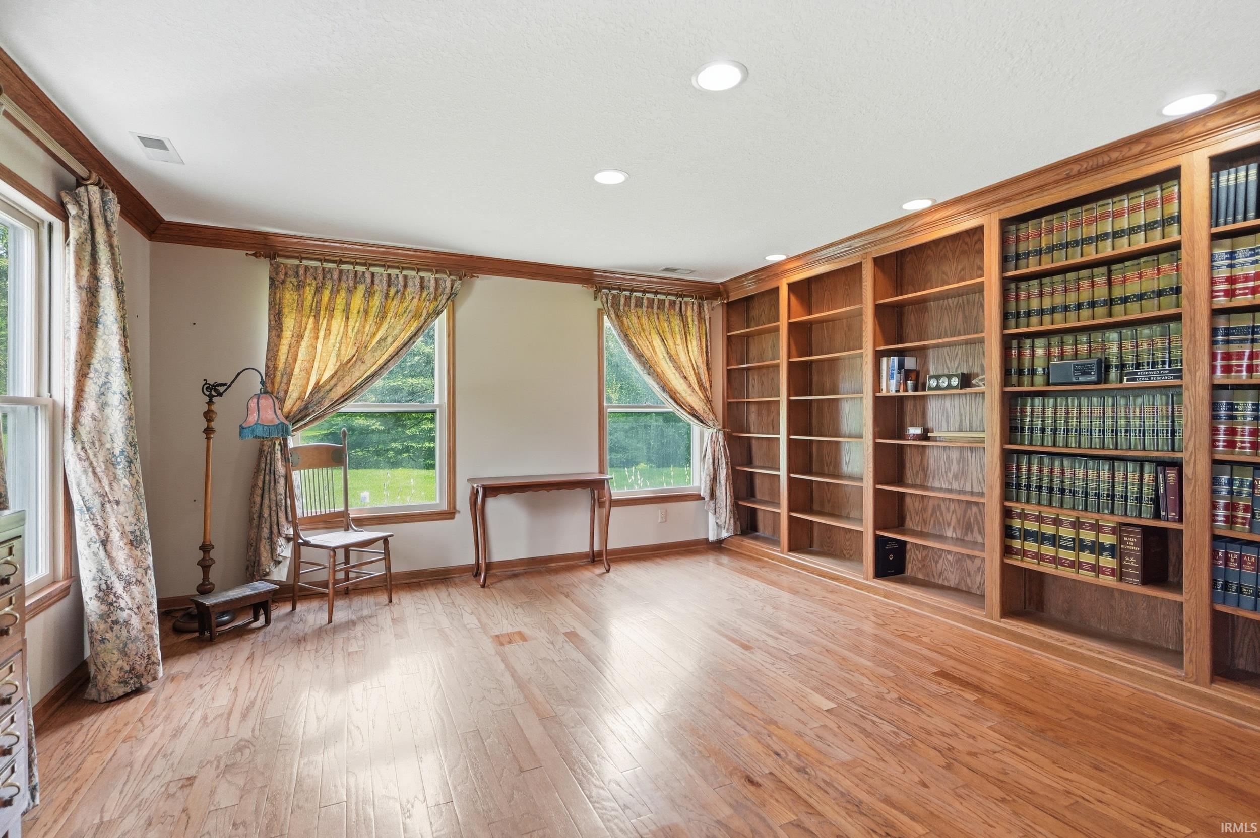 Expansive room featuring extensive built-in wood bookshelves, recessed lighting, wood-finish flooring, and multiple large windows