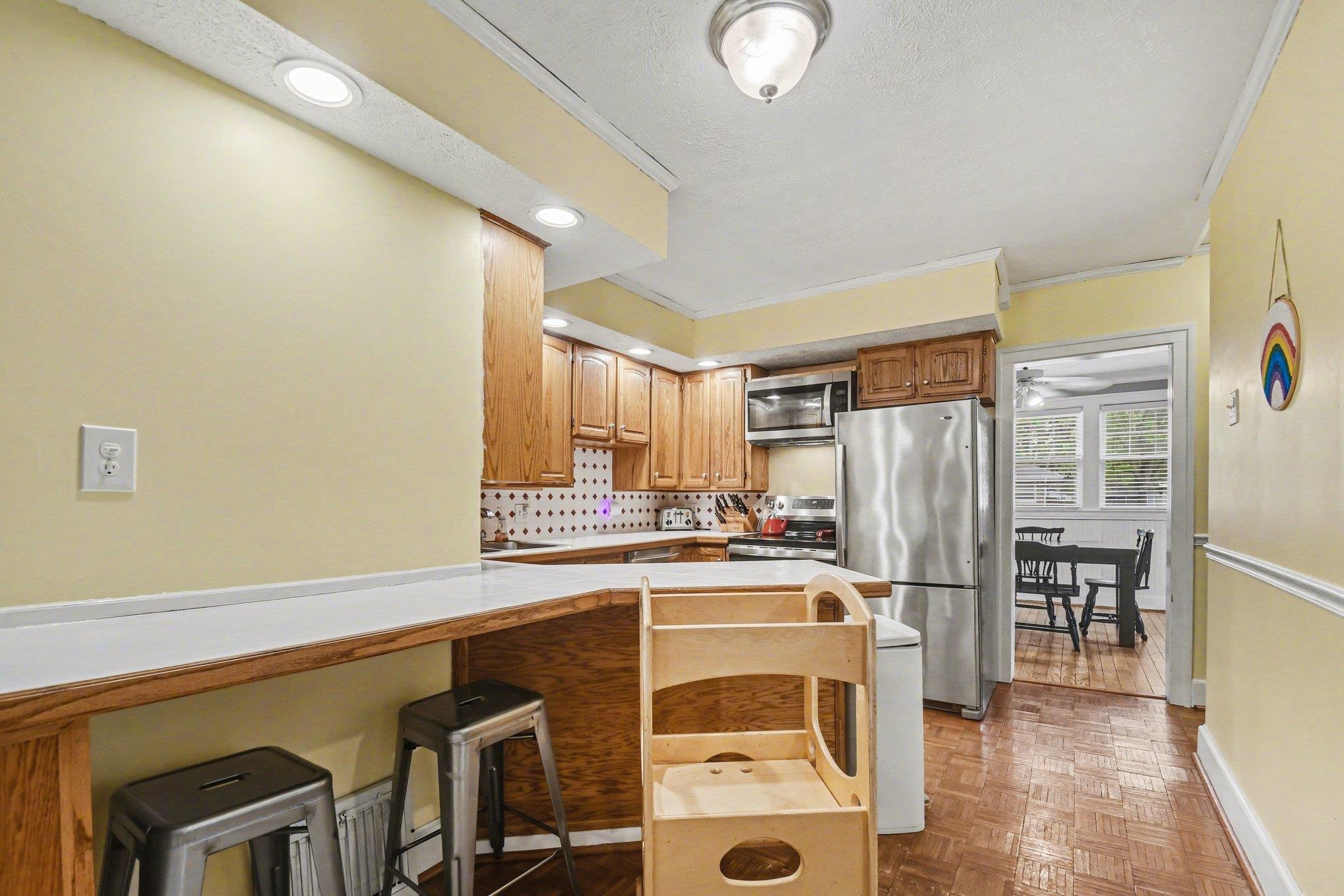 Kitchen featuring wood cabinetry, stainless steel appliances, and a tiled backsplash