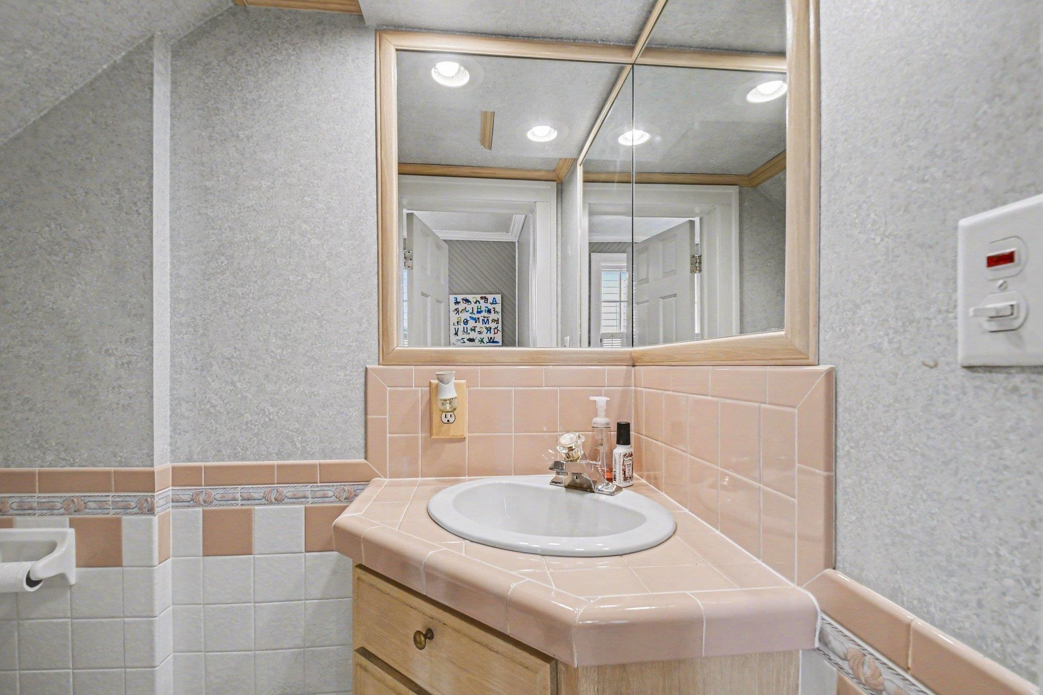 Bathroom vanity featuring a built-in sink, tiled countertop, and wood-finish cabinetry