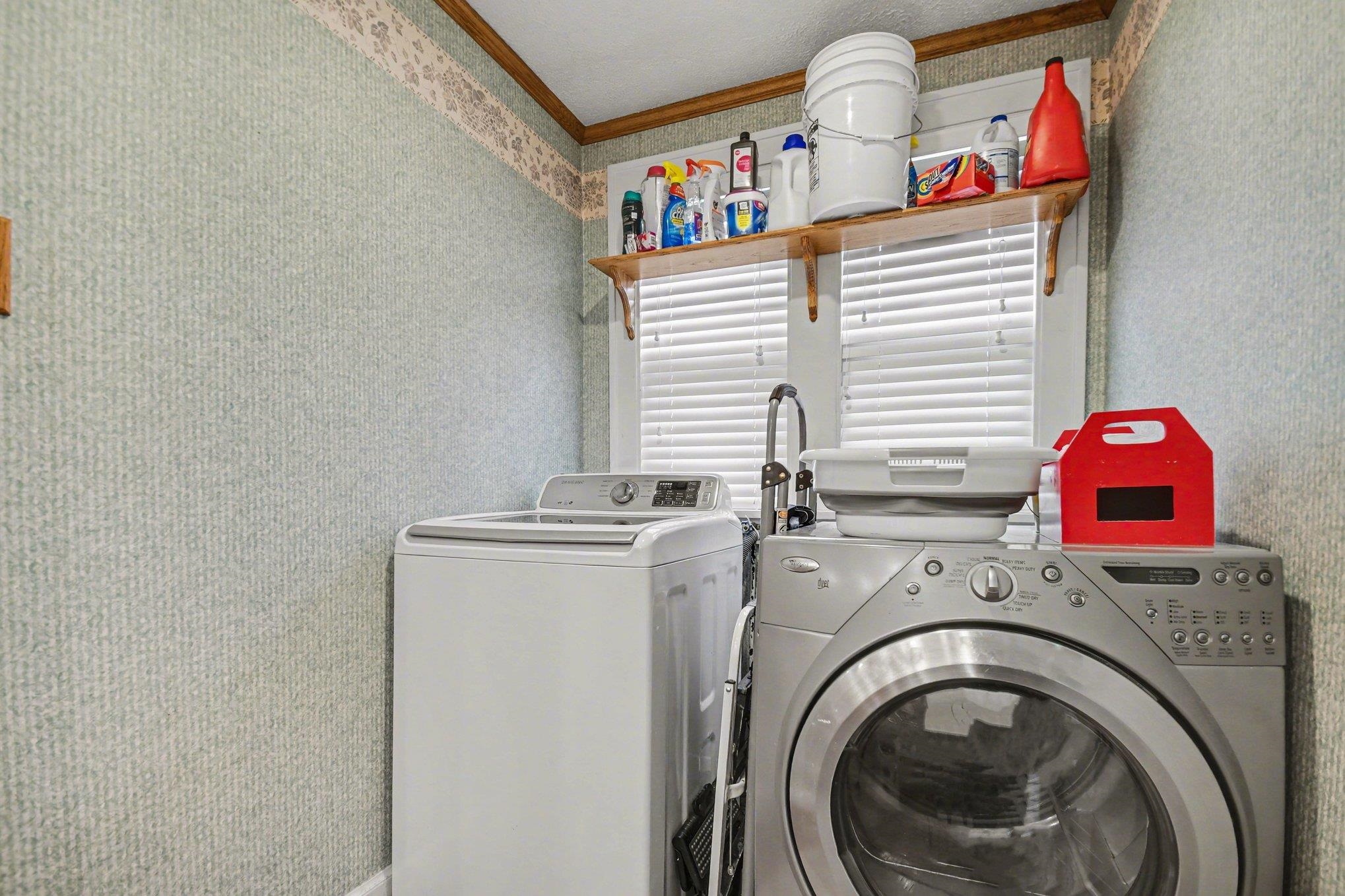 Dedicated laundry area featuring a window with horizontal blinds, wall-mounted shelving, and a decorative border