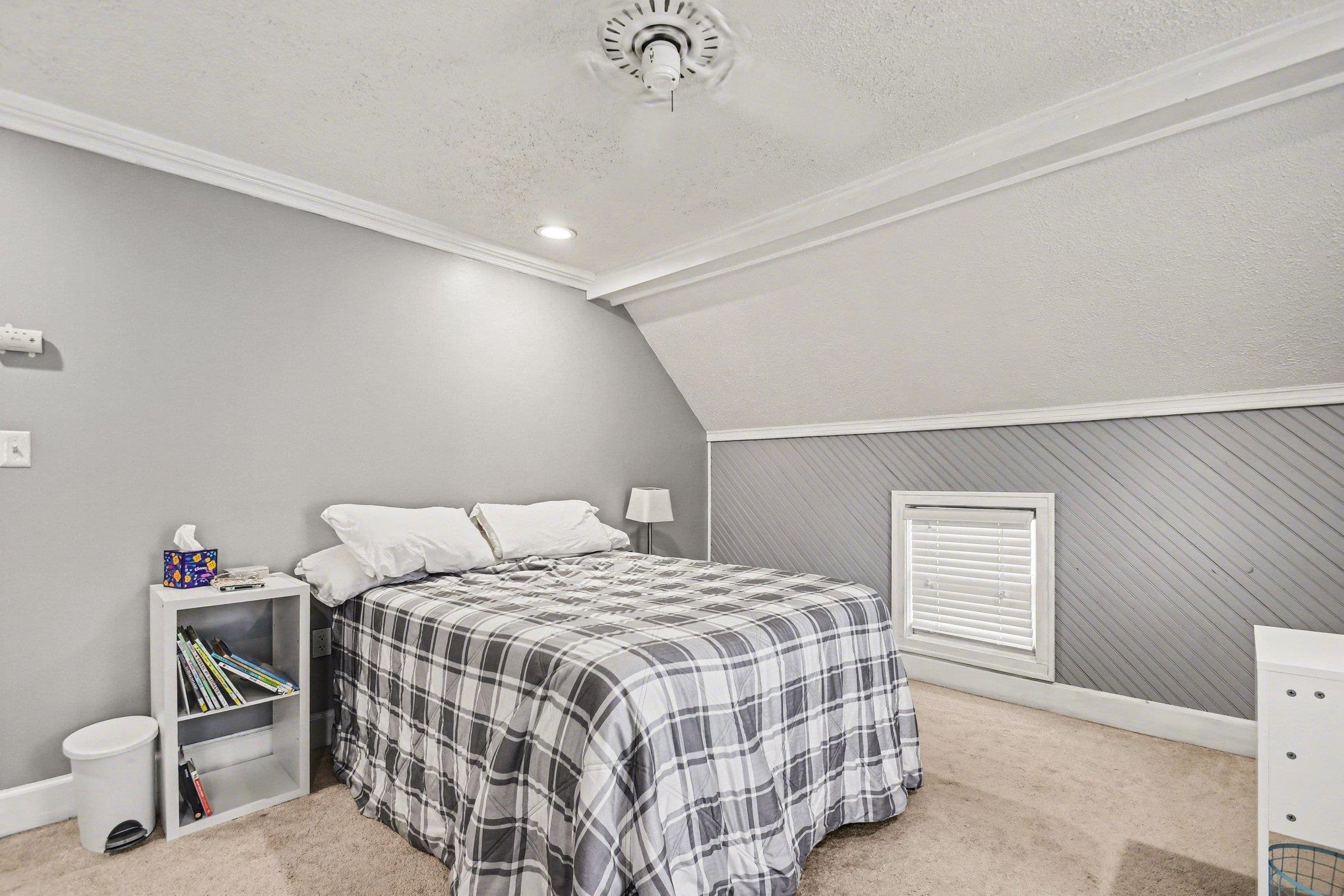 Carpeted room featuring a sloped ceiling, recessed lighting, crown molding, and a single window with blinds