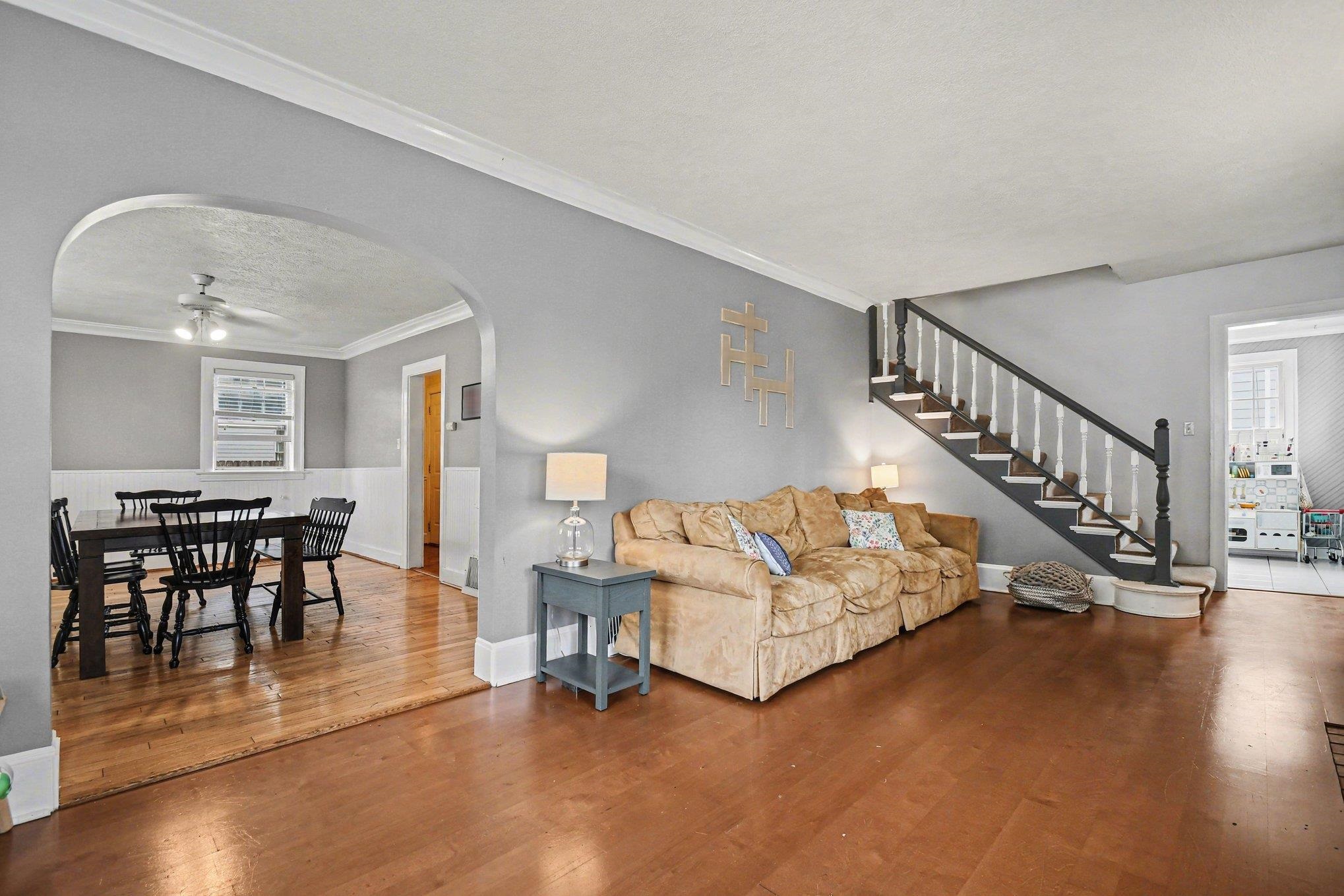 Hardwood-style flooring extends through the main living area with a staircase featuring dark wood newel posts and white balusters