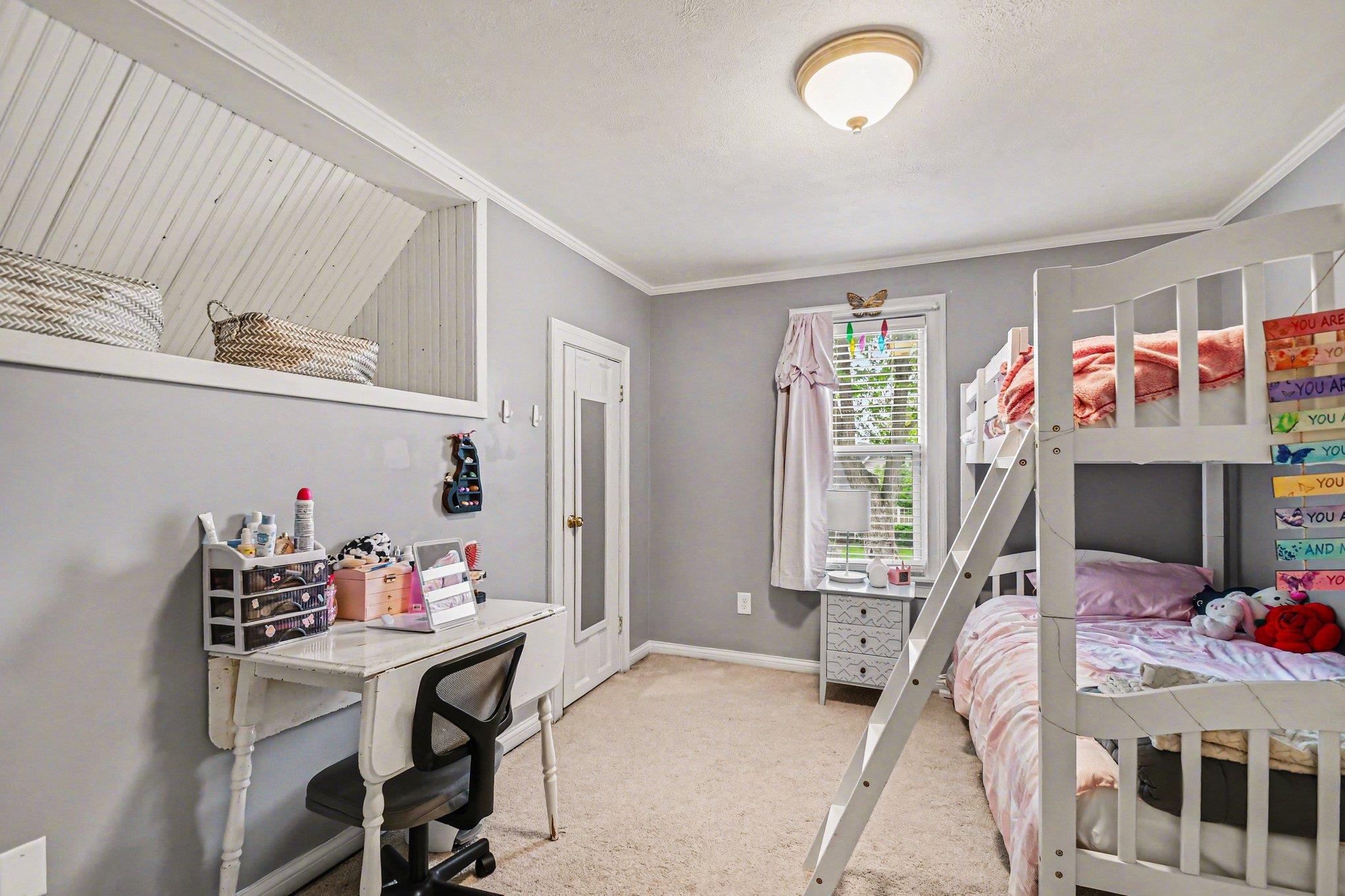 Carpeted room with a ceiling-mounted light fixture, a window with blinds and drapes, and a built-in wall niche with beadboard paneling