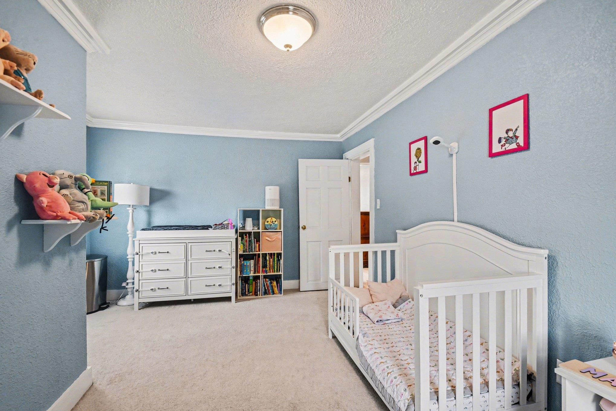 Bedroom featuring crown molding, neutral wall-to-wall carpeting, and a flush mount ceiling light fixture