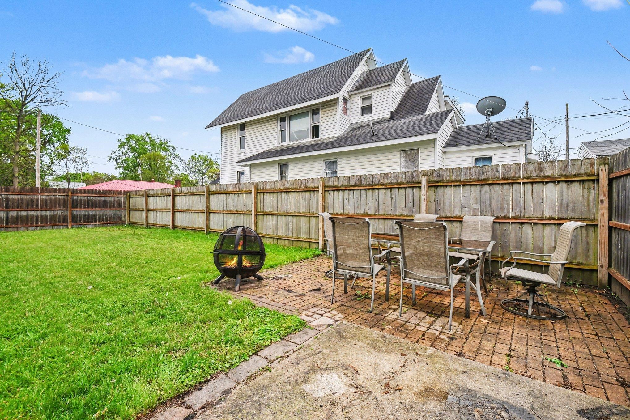 Fenced backyard with a spacious lawn and a brick paver patio