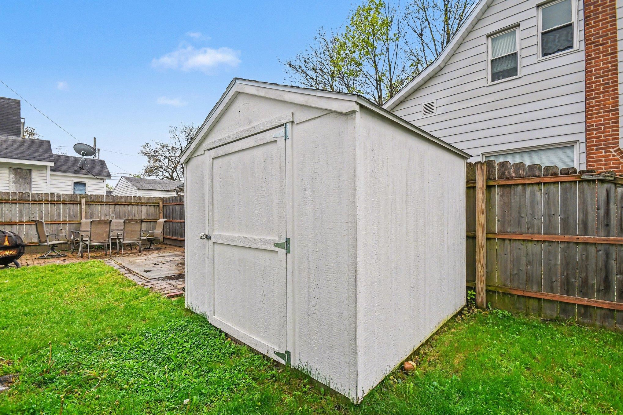 Backyard featuring a white storage shed, a wood fence, and a patio area