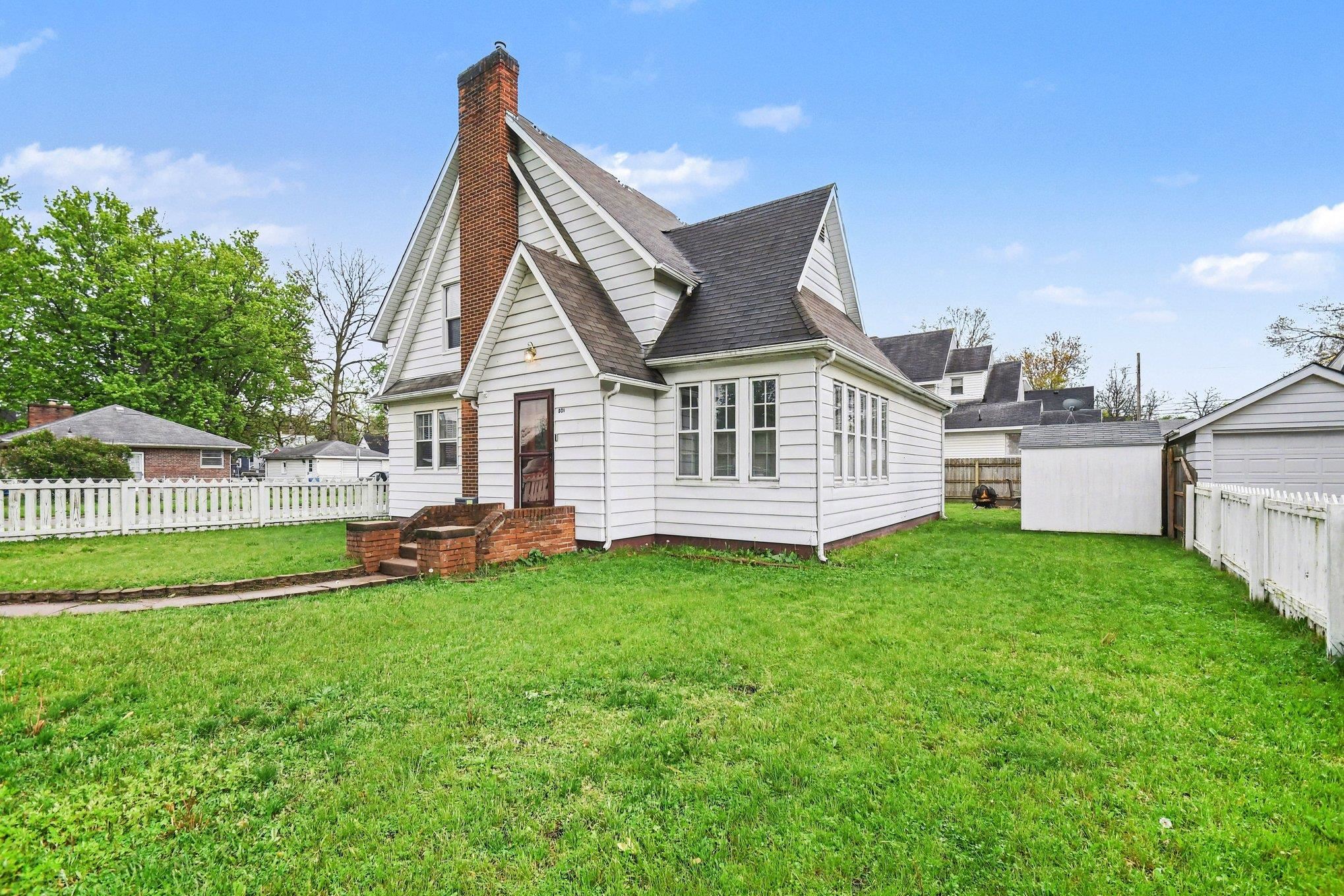 White-sided residence featuring a prominent brick chimney and a gabled roofline