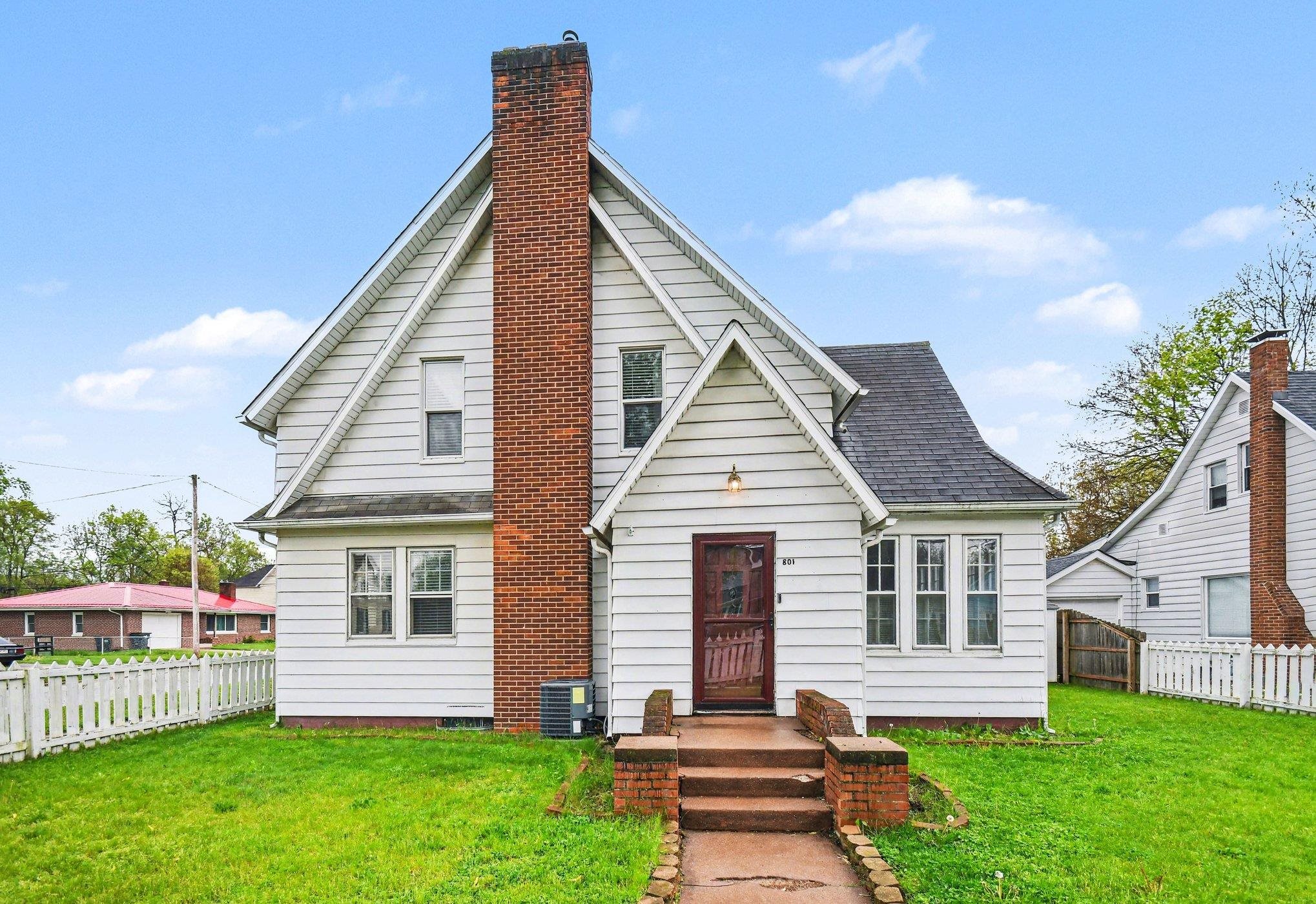 White siding exterior with a prominent brick chimney