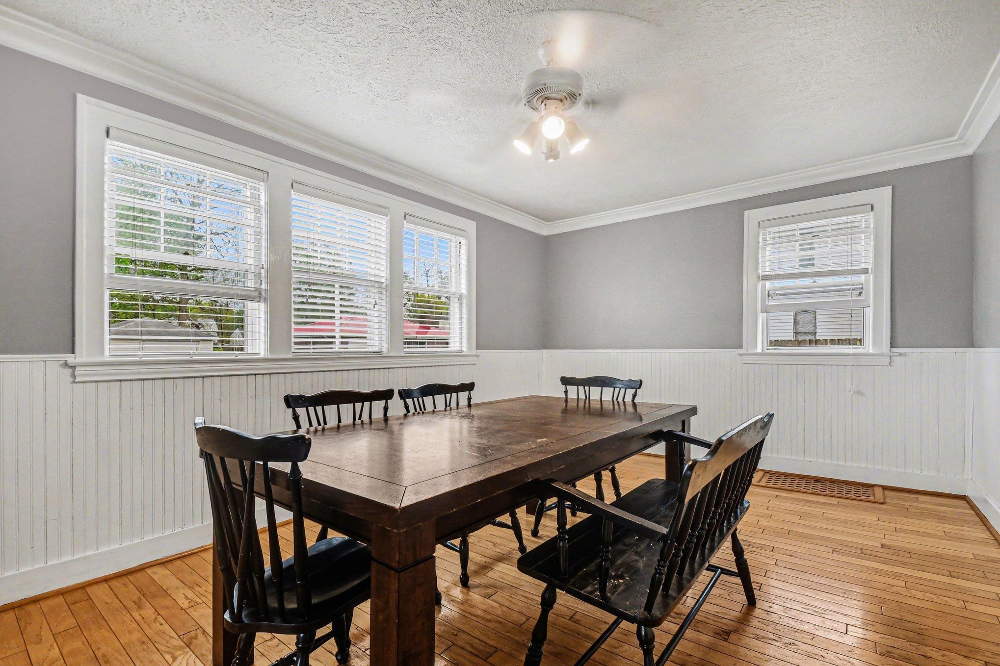 Hardwood flooring throughout featuring white beadboard wainscoting and crown molding