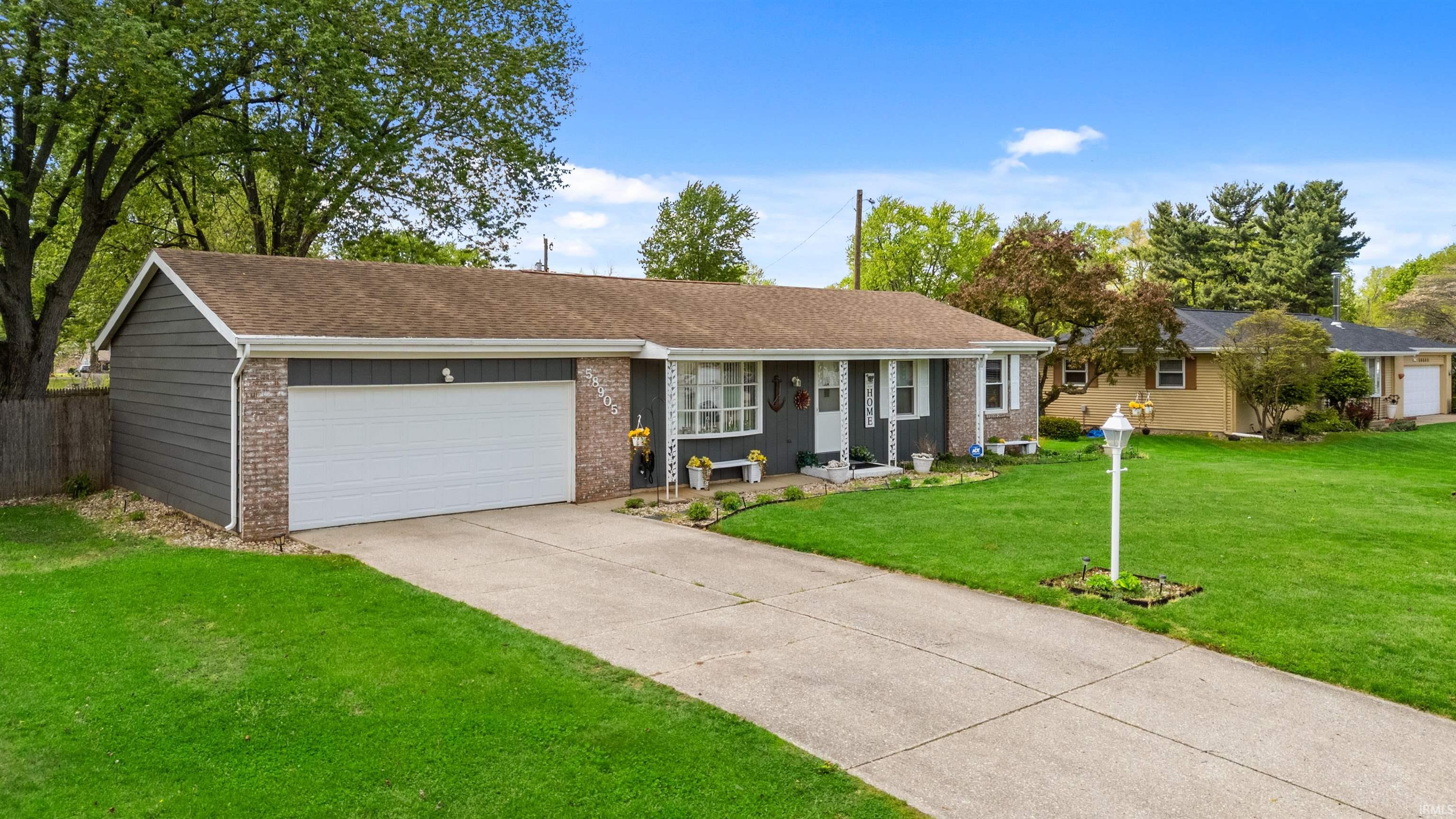 Single-story residence featuring a two-car garage, gray siding, and brick accents