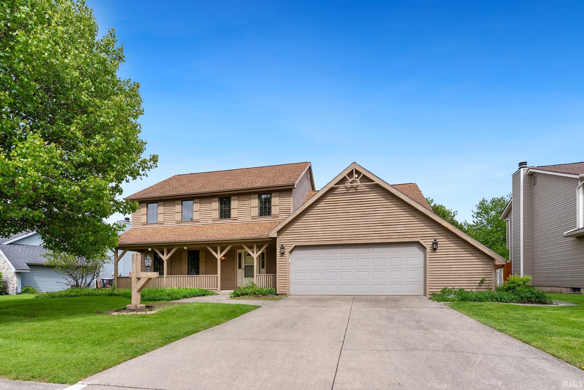 Two-story home featuring a full-width covered porch, attached two-car garage, and a concrete driveway