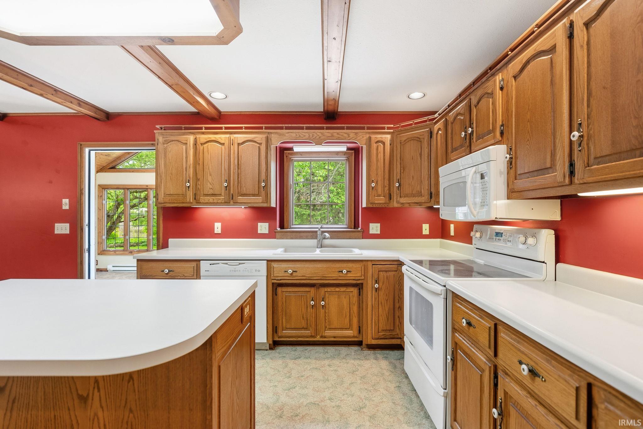 Kitchen featuring extensive wood cabinetry, white countertops, built-in white appliances, and a central island