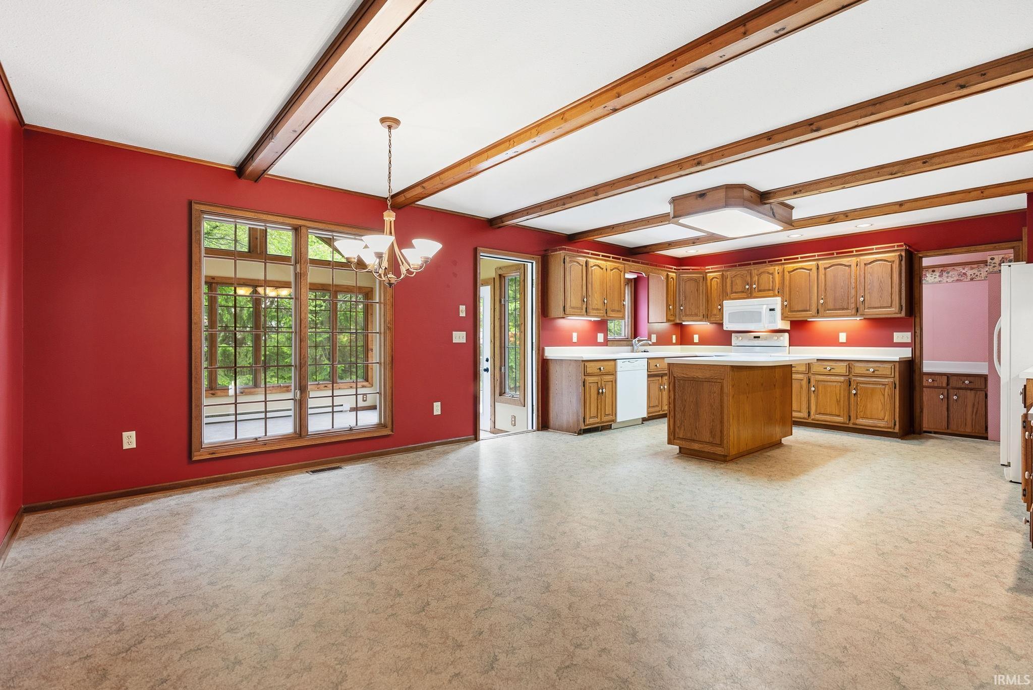 Kitchen and dining area featuring a central island, wood cabinetry, white appliances, and a chandelier