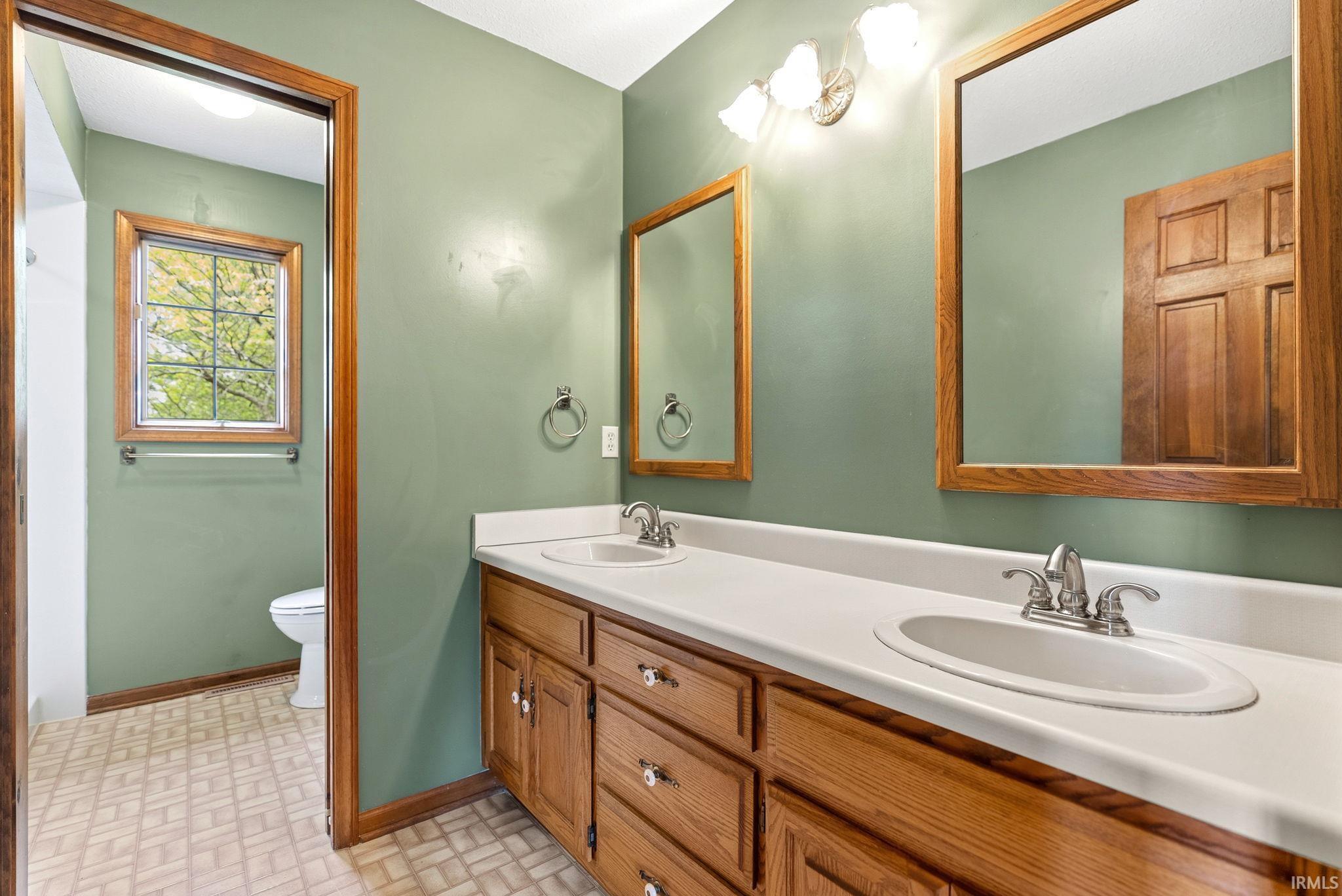 Bathroom featuring a double vanity with wood-finish cabinetry, white countertops, and integrated sinks