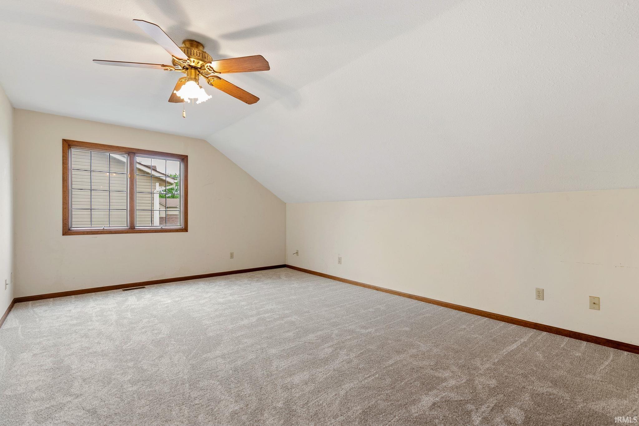 Spacious room with a vaulted ceiling and an angled wall