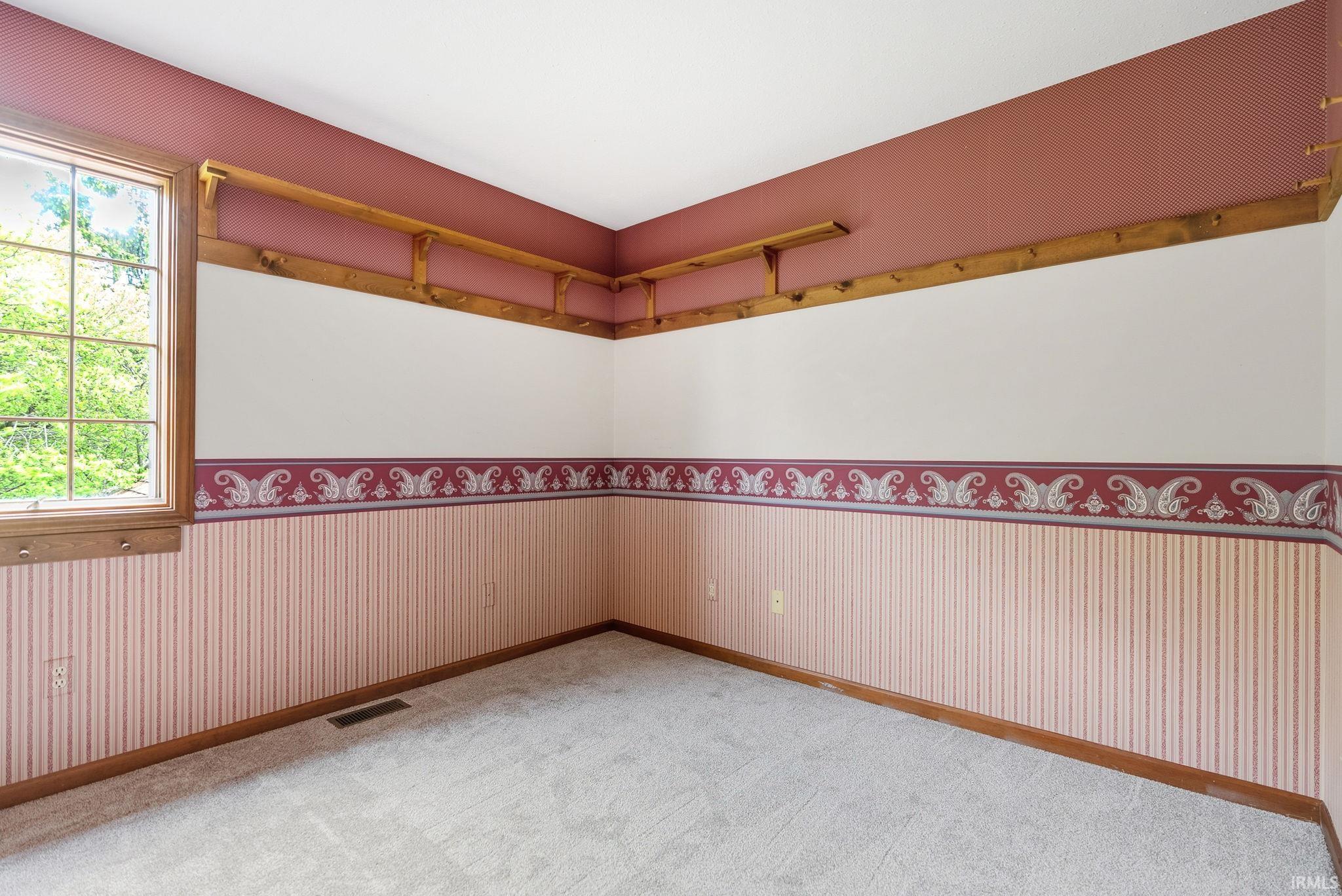 Room featuring light gray carpeting, wood-frame window, and wood trim