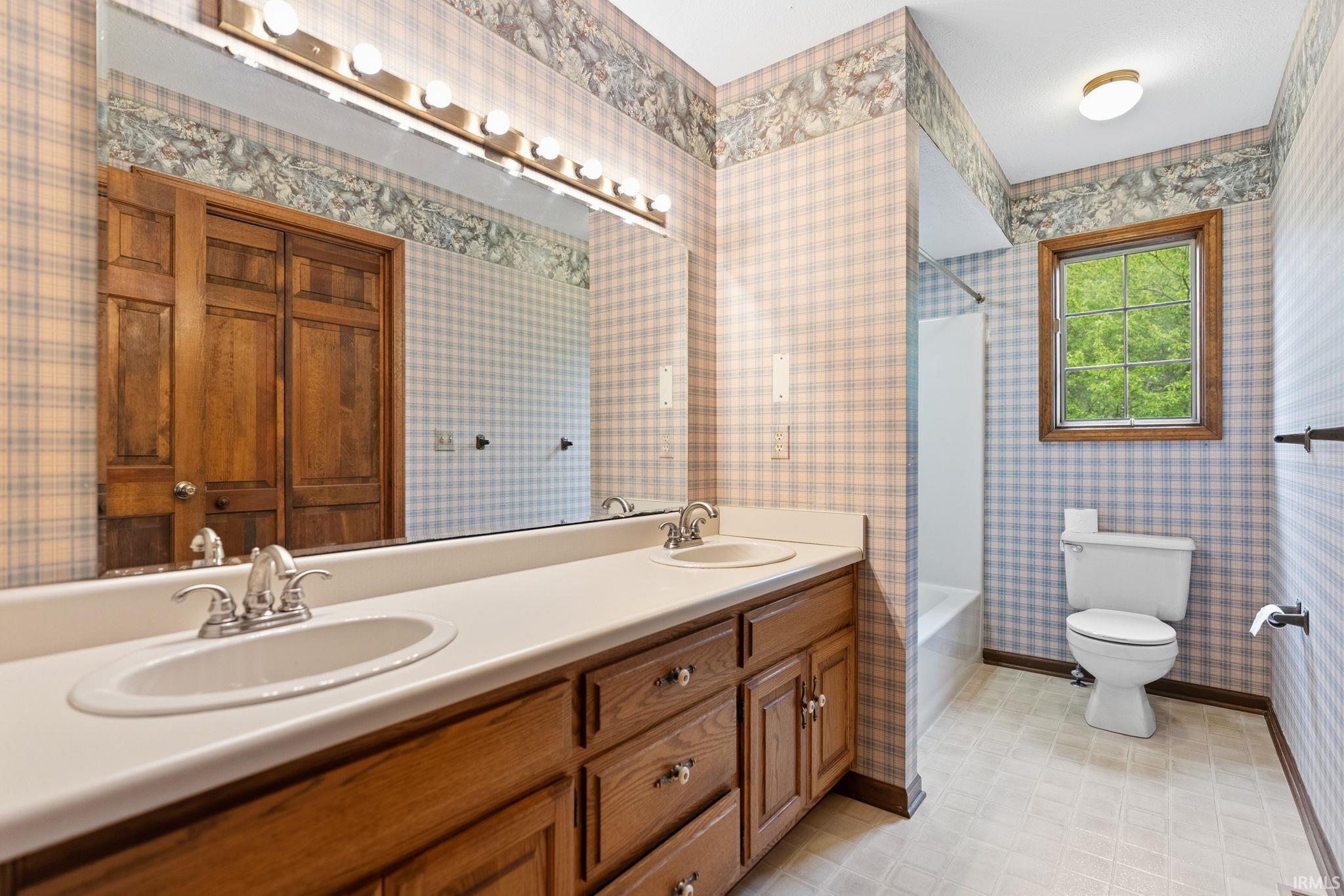 Dual vanity featuring integrated sinks, chrome faucets, and wood cabinetry