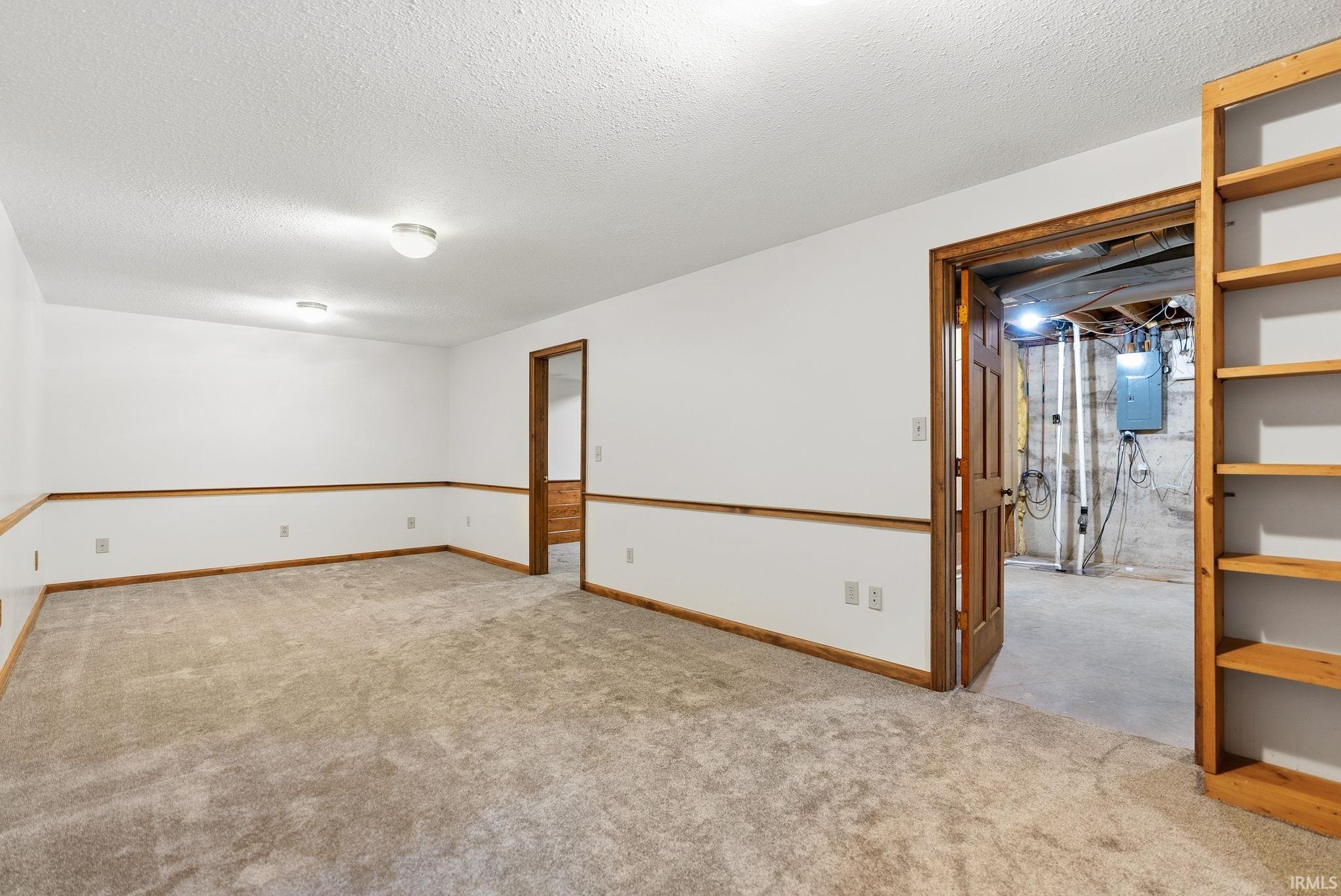 Carpeted room featuring white walls with wood trim, recessed lighting, and built-in wood shelving