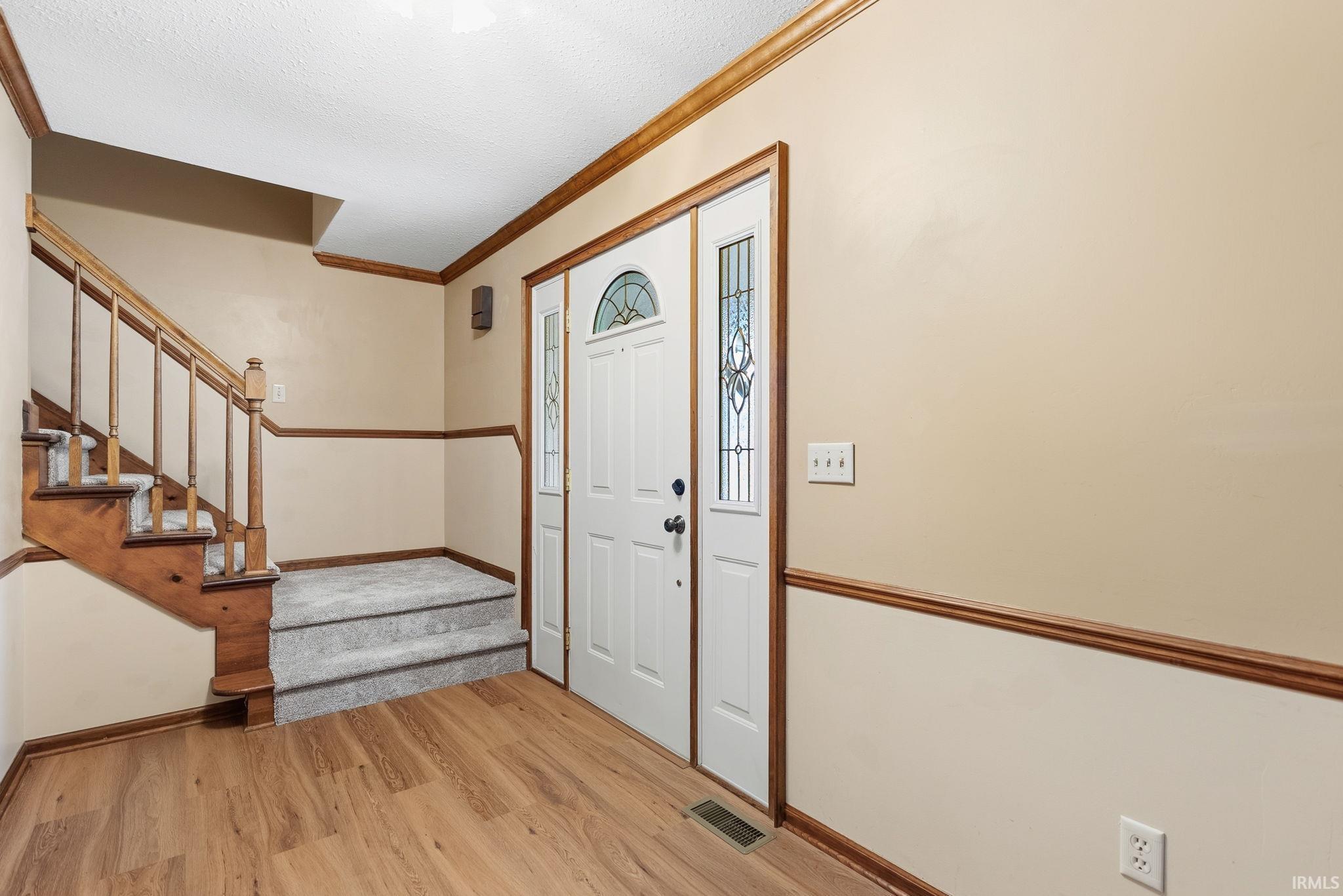 Entryway featuring a white paneled door with decorative glass inserts, sidelights, and transom window